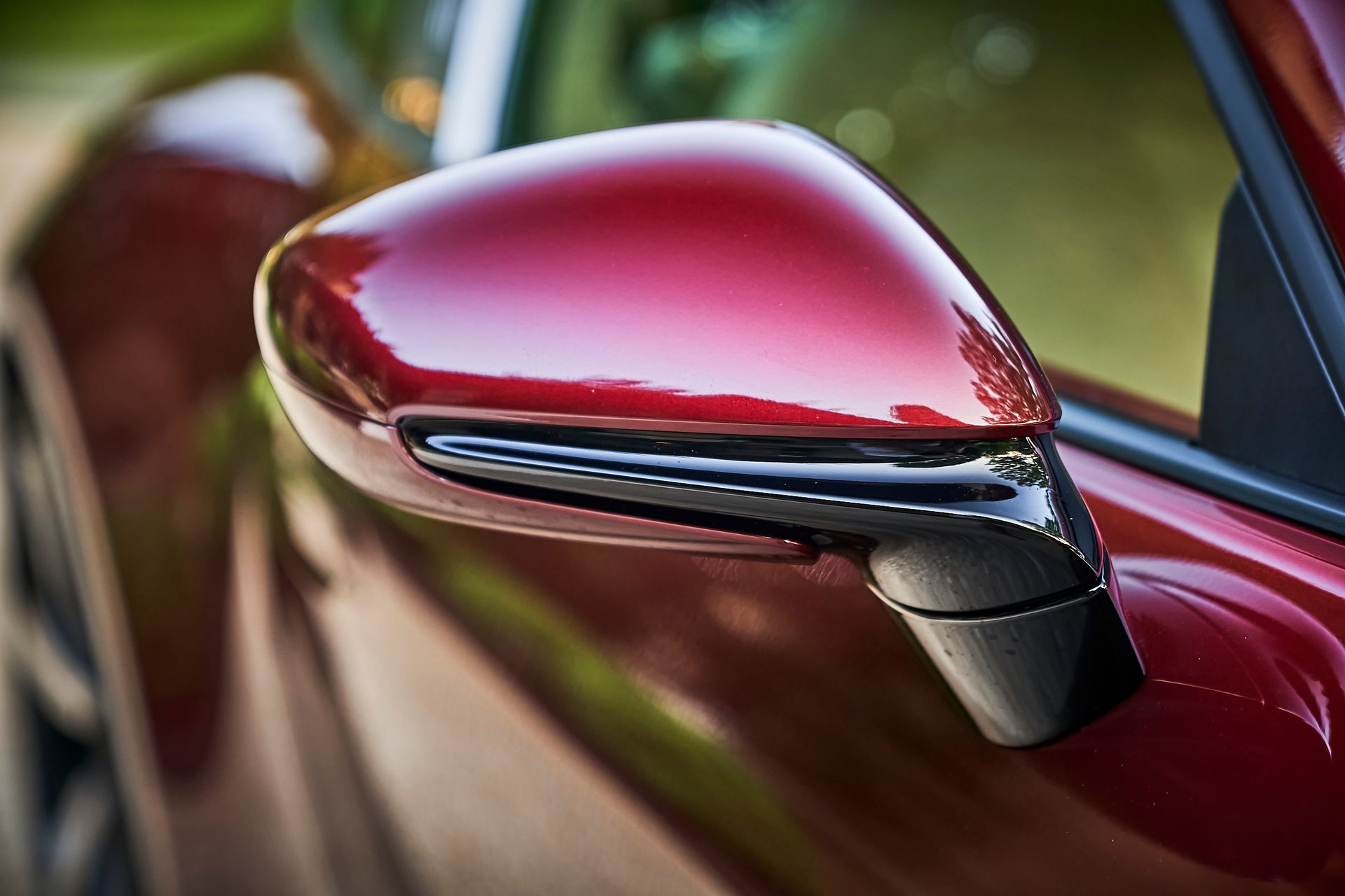 A close up of a red car 's side mirror.