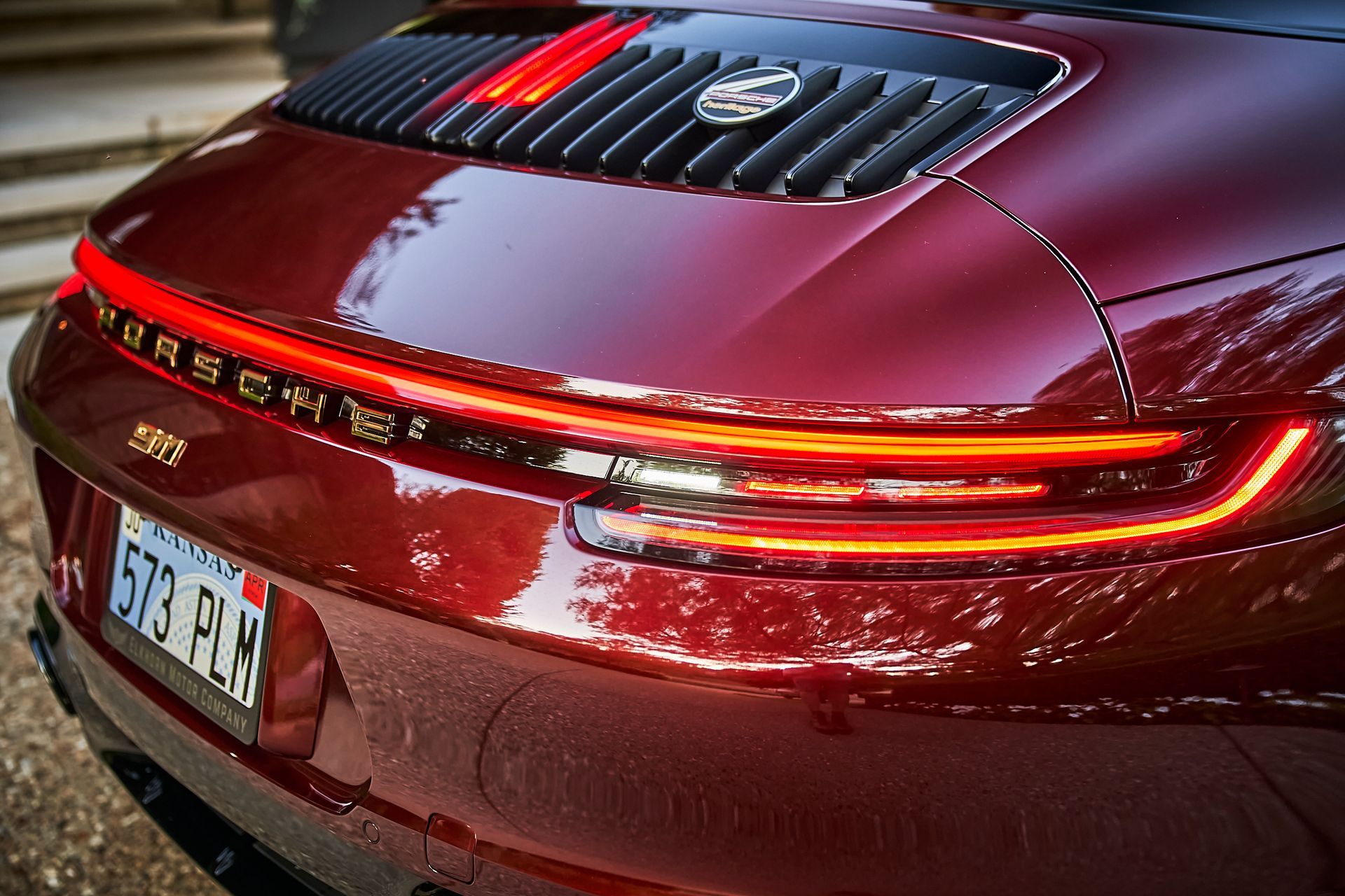 A red porsche 911 carrera is parked on the side of the road.
