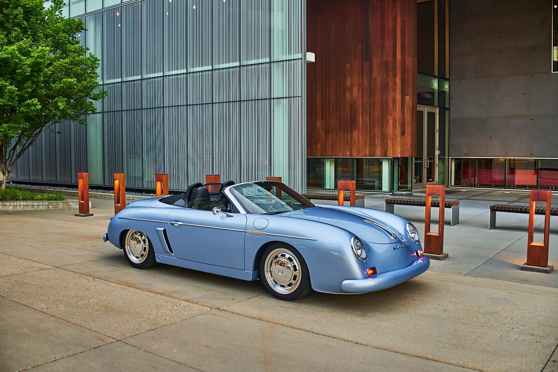 Light blue convertible sports car parked in front of a modern building with a wooden exterior.