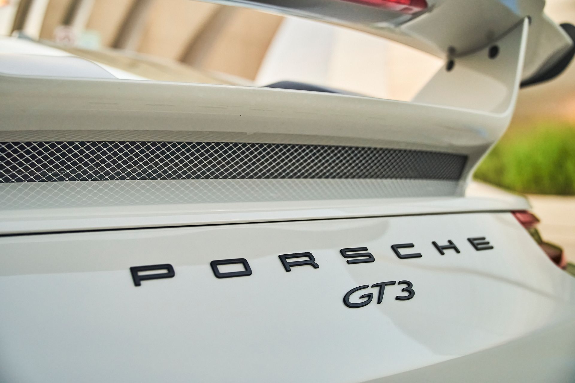 The rear end of a white porsche gt3 is shown.