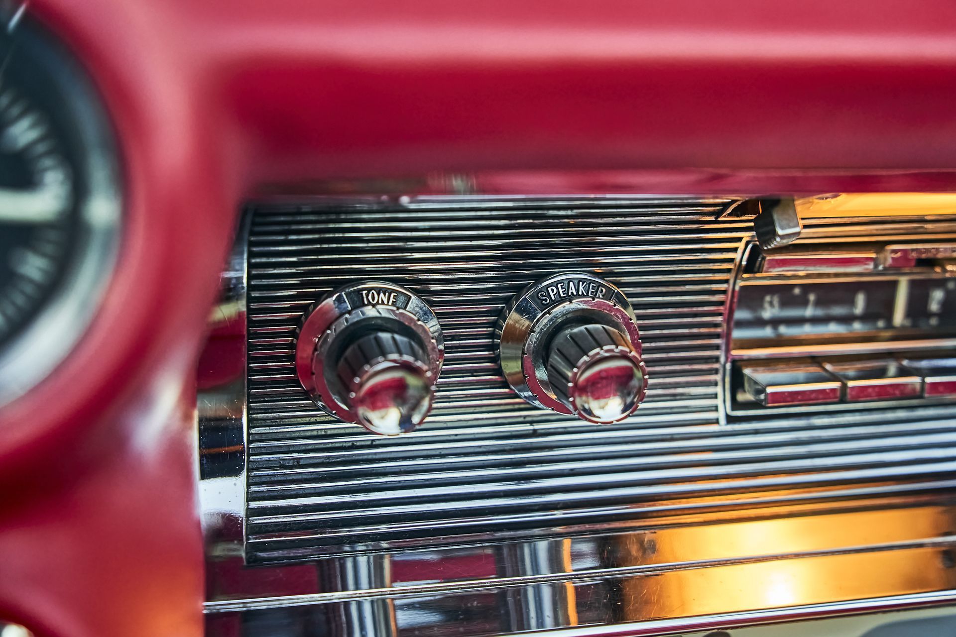 A close up of a red car dashboard with a clock in the background.