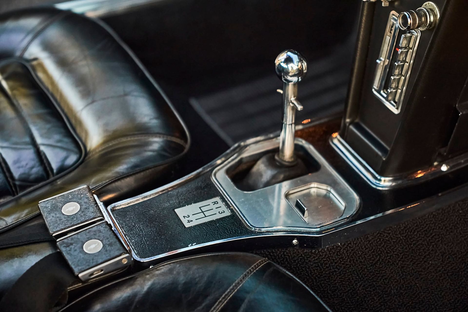 Close-up of a classic car's interior: leather seats, manual gear shift, and metallic console details.