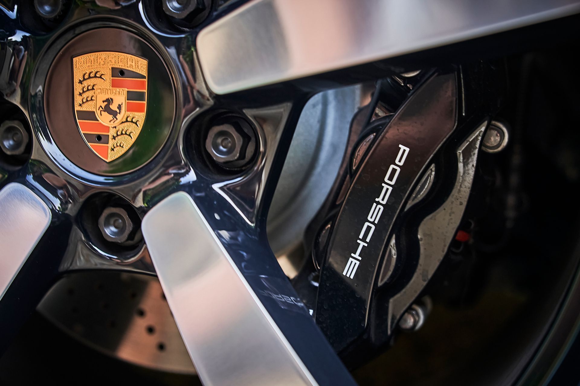 A close up of a porsche brake caliper on a wheel