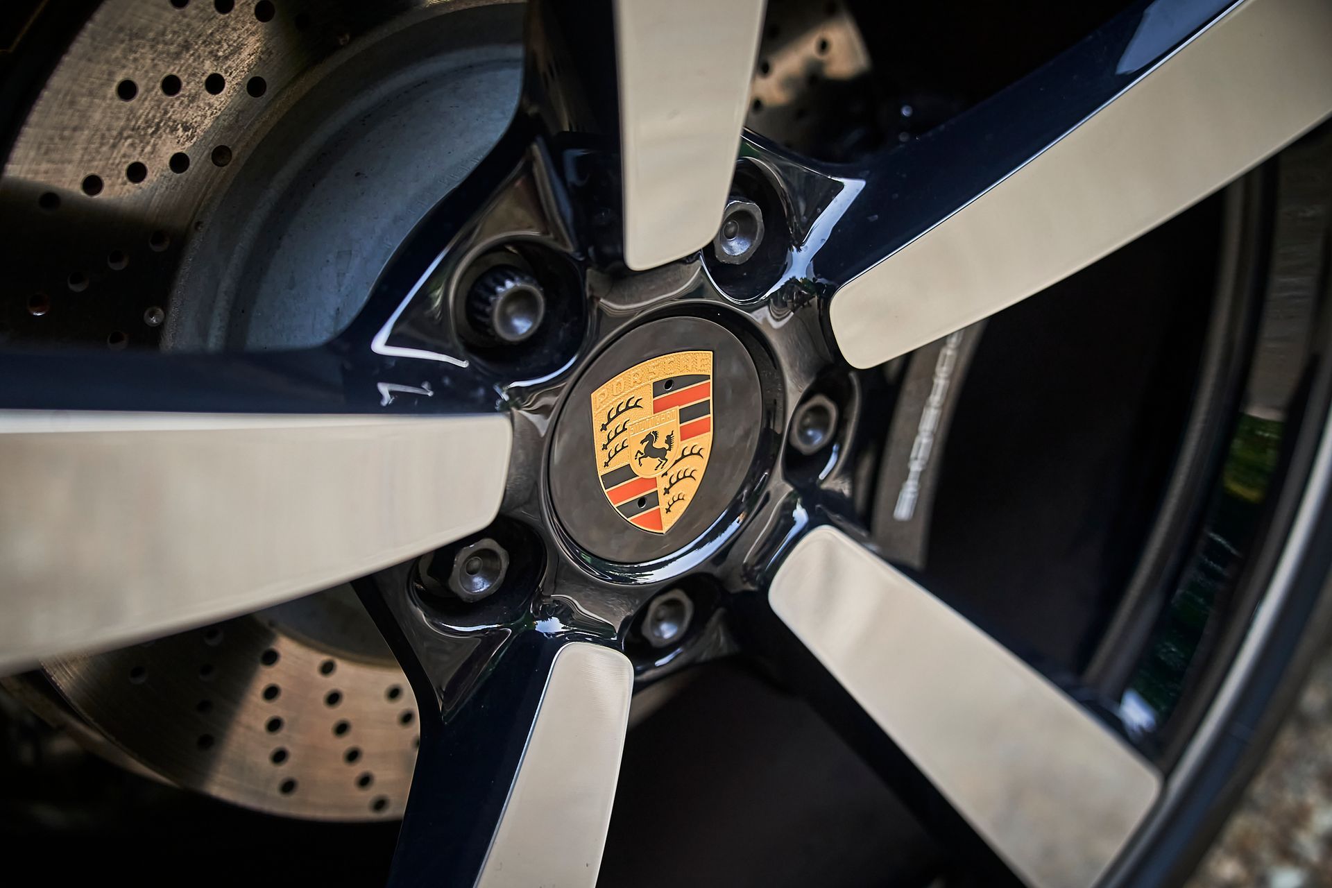 A close up of a porsche wheel with a logo on it.