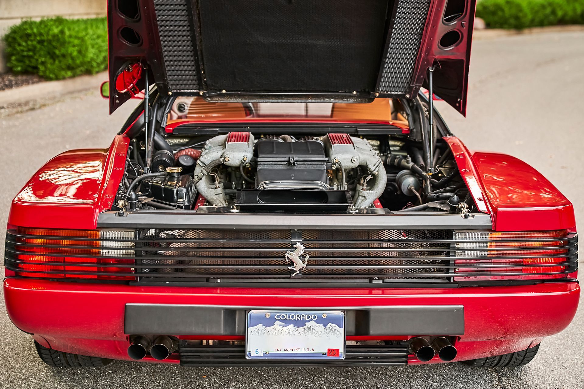 The hood of a red sports car is open and the engine is visible.