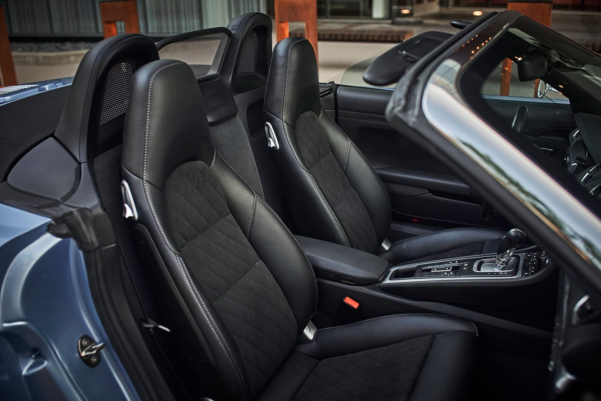Interior of a dark blue convertible car. Black leather seats are visible with the door open.