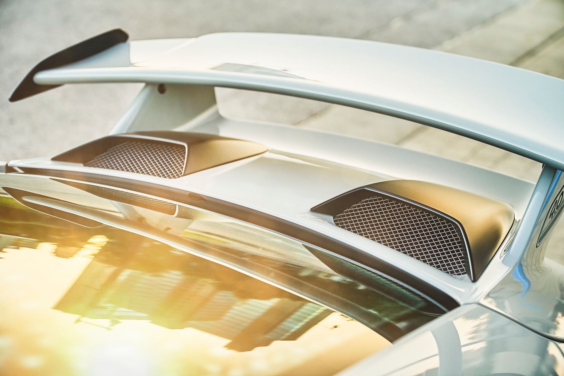 A close up of the rear wing of a white sports car.