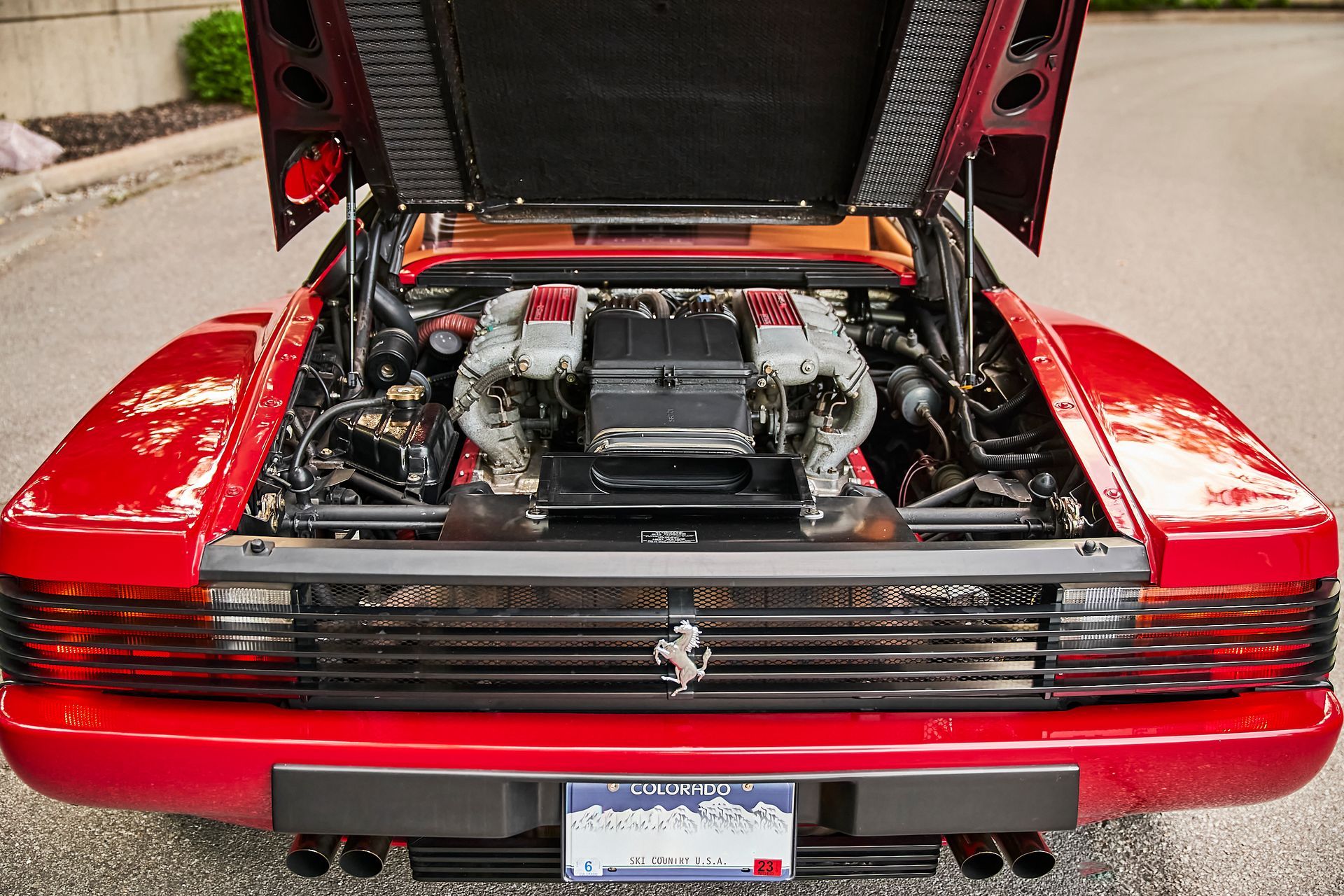 The engine of a red ferrari with the hood open
