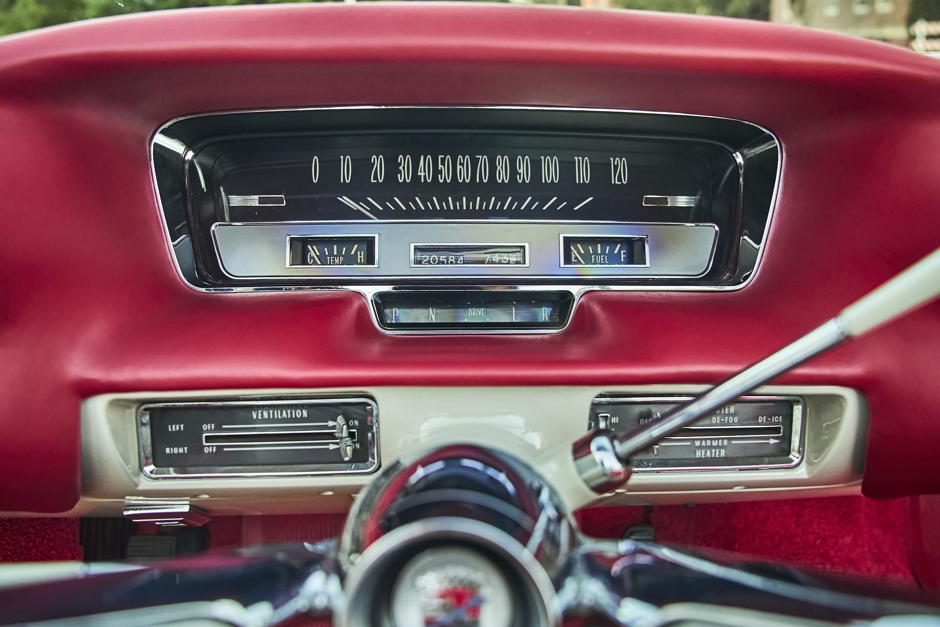 A close up of a car dashboard with a speedometer and a steering wheel.