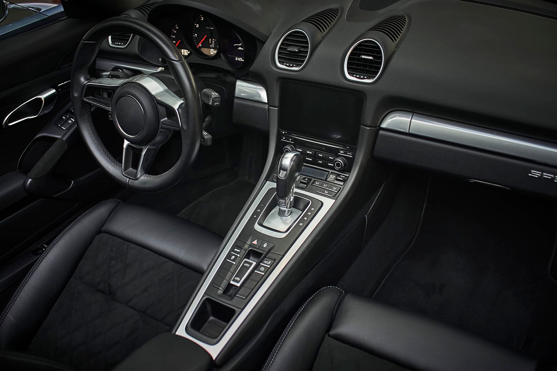 Black leather car interior with a steering wheel, dashboard, and center console.