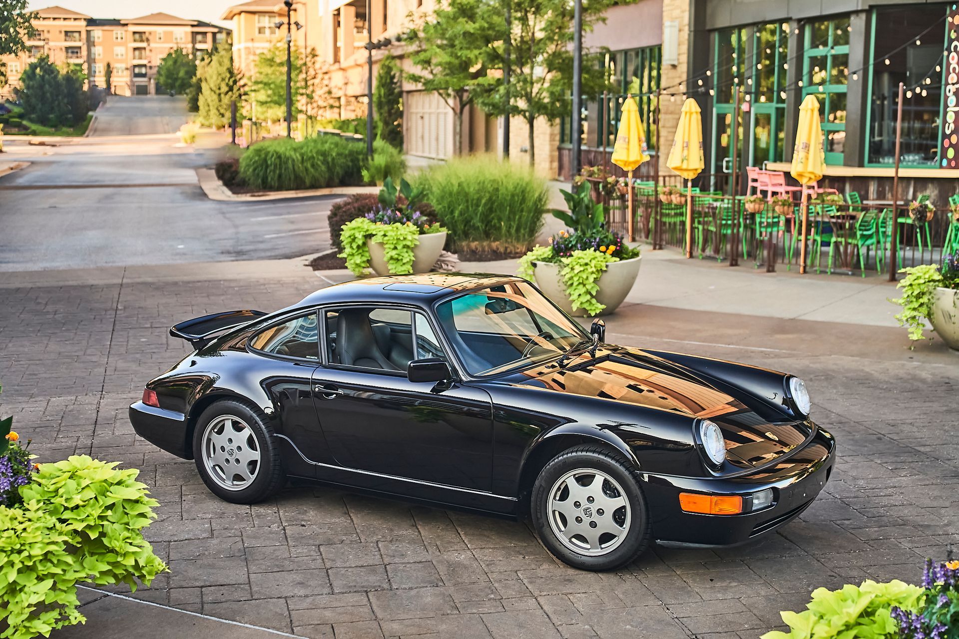 A black porsche targa is parked in front of a restaurant.