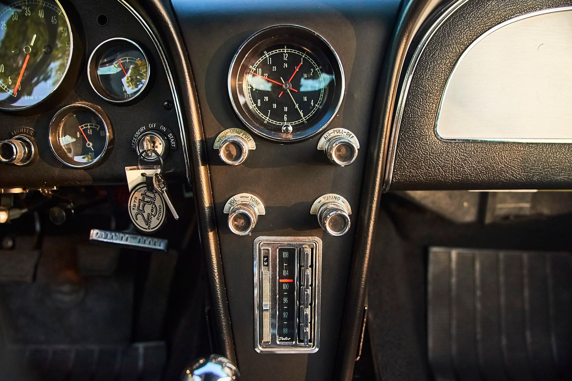 Dashboard of a vintage car with black gauges, chrome knobs, and a classic radio.