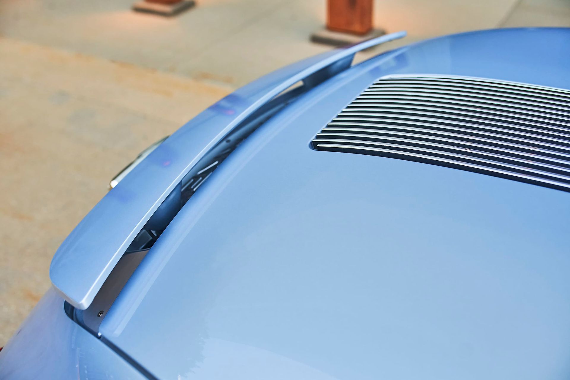 Close-up of a light blue car roof with a rear spoiler and a vent.