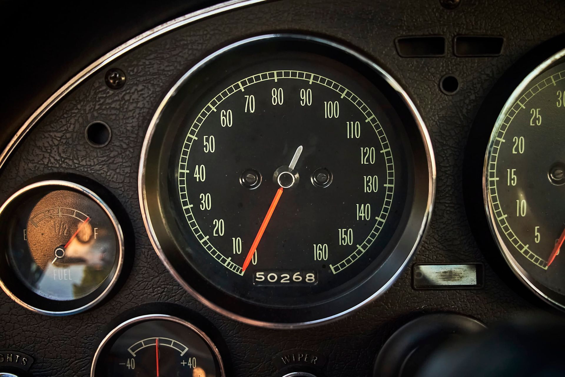 Black car dashboard with speedometer showing the car is traveling at about 50 mph. Other gauges are also visible.