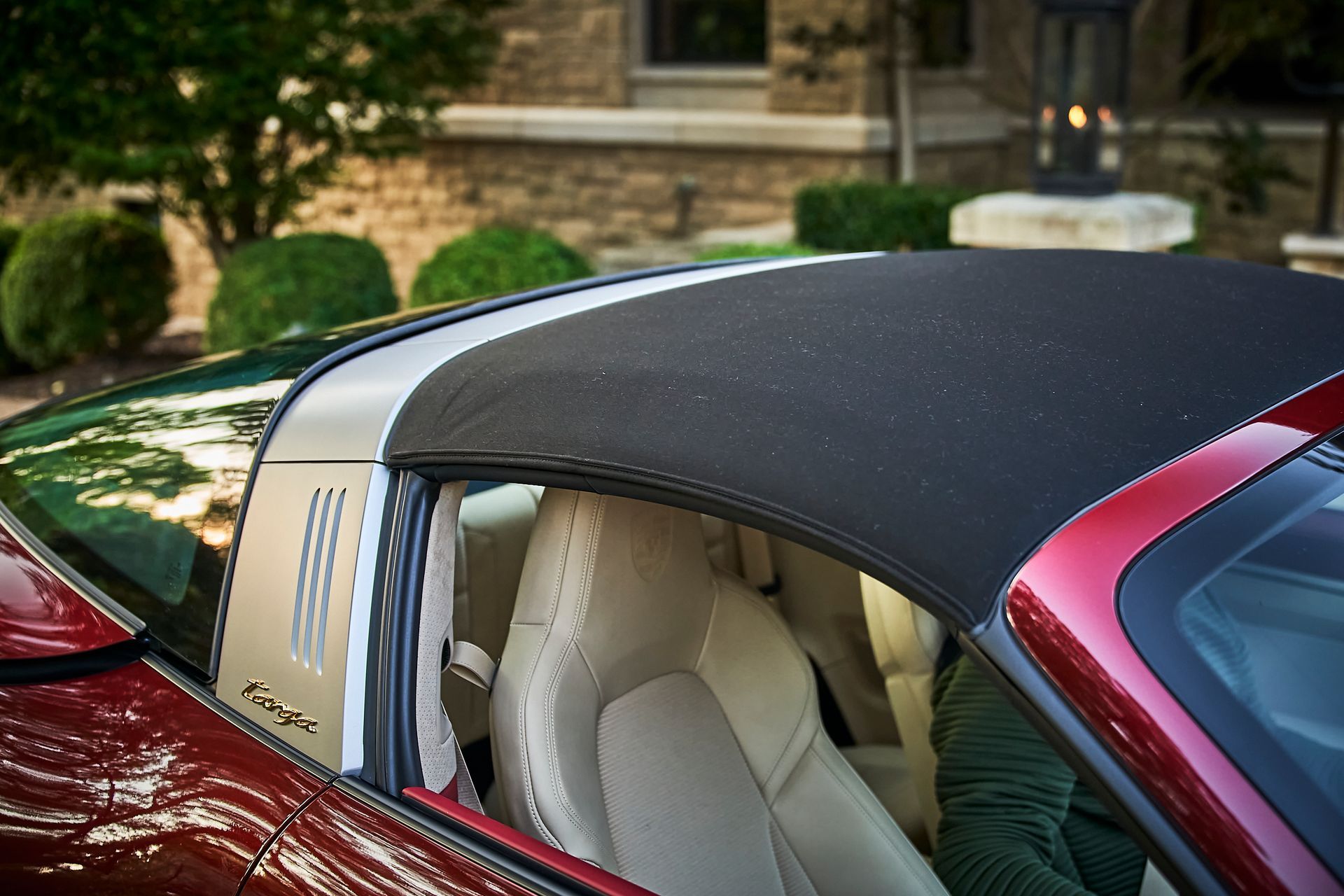 A red sports car with a black top is parked in front of a house.