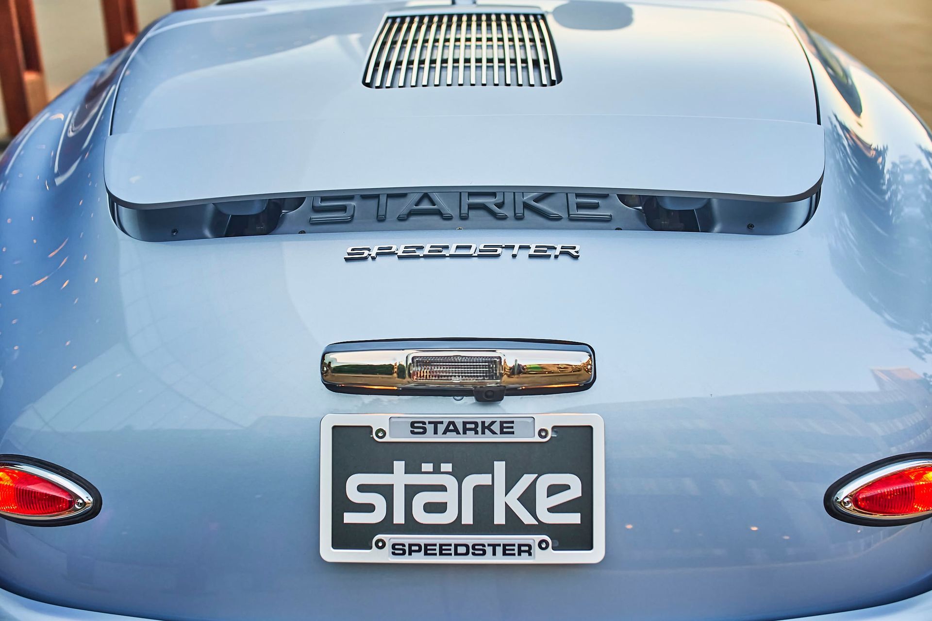 Rear view of a light blue Starke Speedster car, license plate and logo visible, with chrome detailing and red taillights.