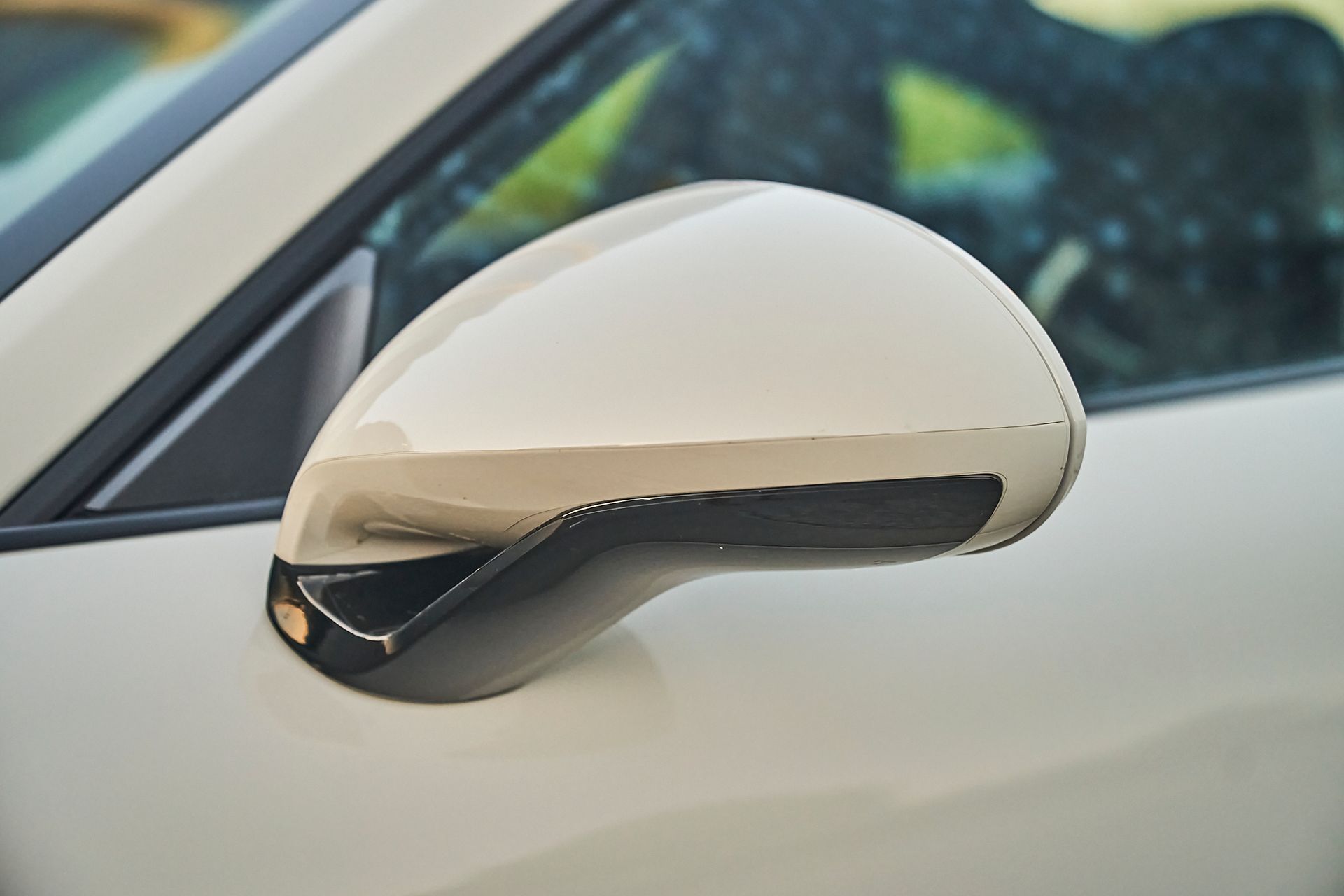A close up of a side view mirror on a white car.