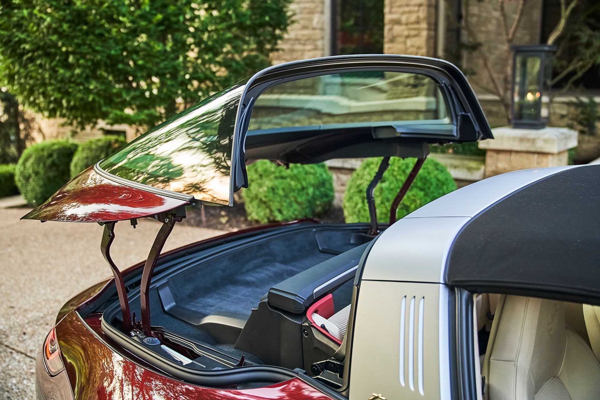 A red sports car with the top down is parked in front of a house.