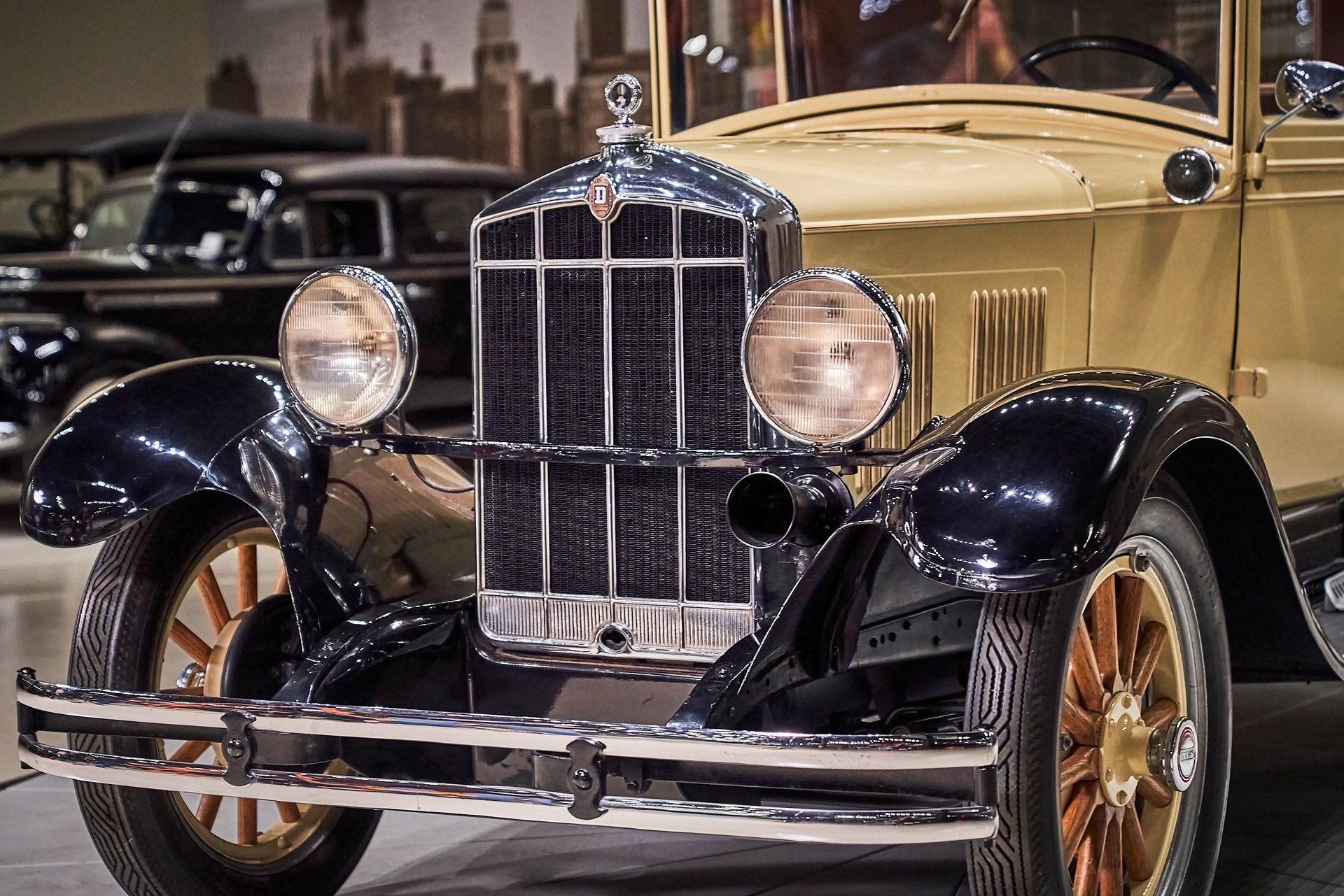 An old car is parked in a garage with a city in the background