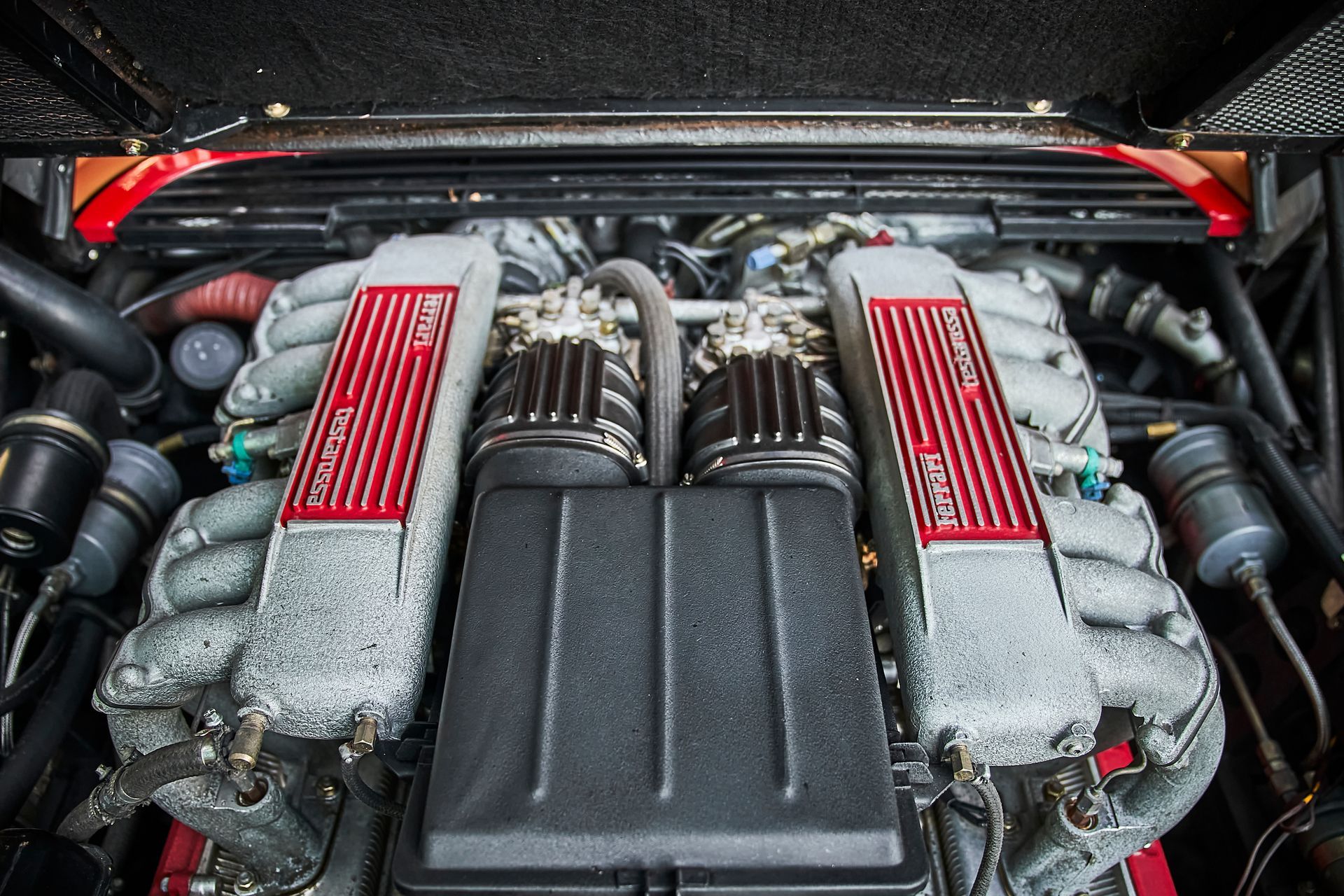 A close up of the engine of a ferrari with the hood open.