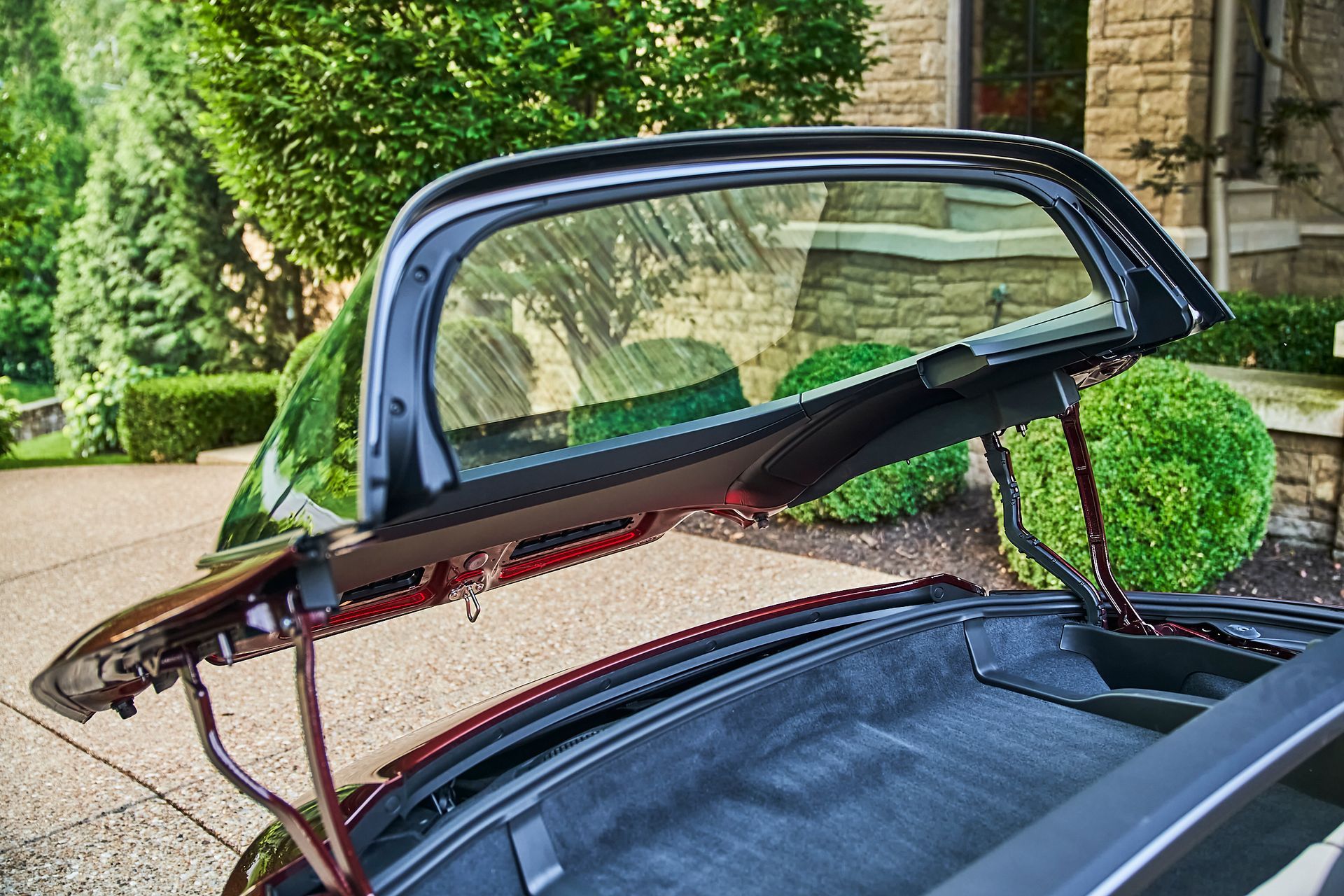 A car with the trunk open is parked in front of a house.