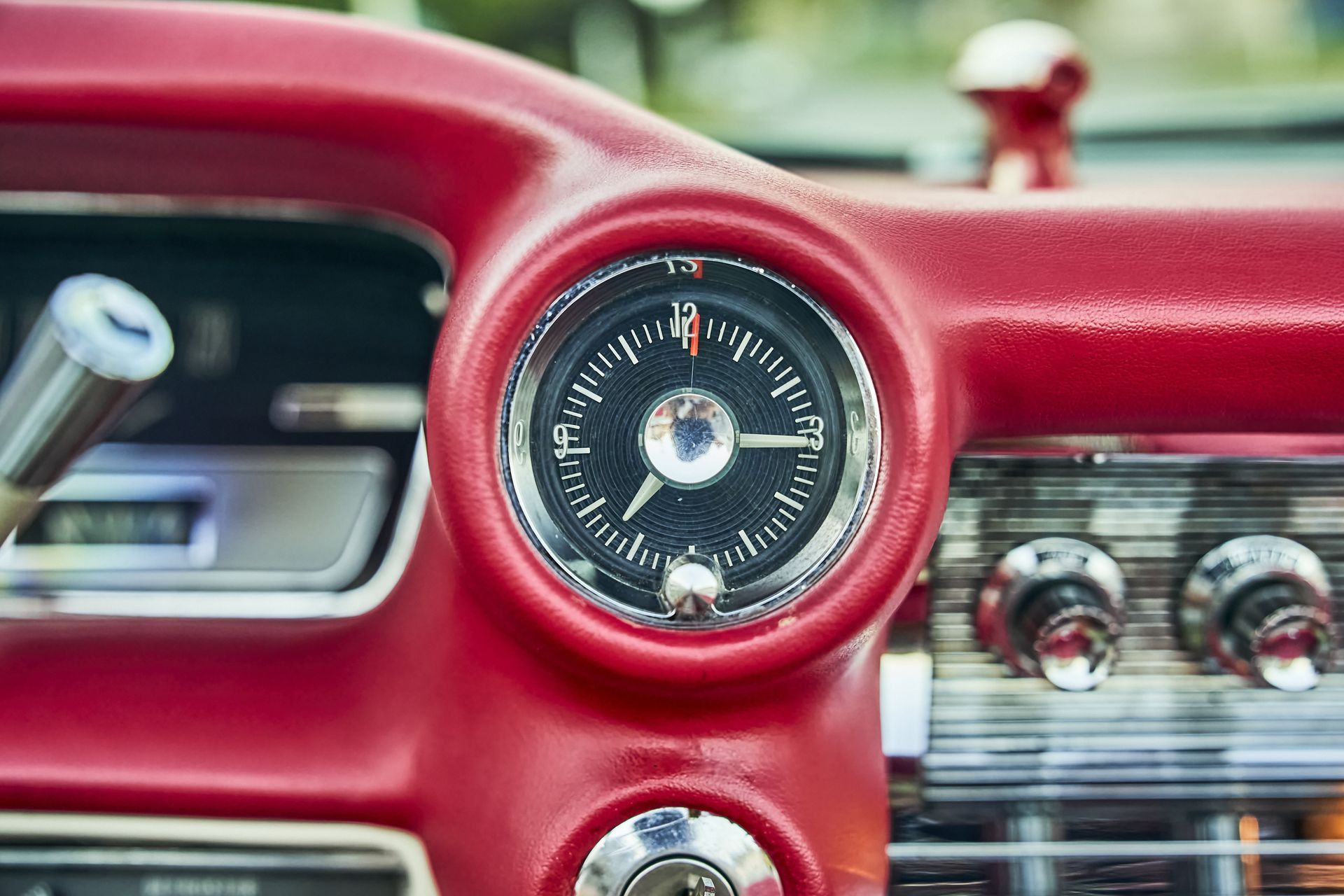 A close up of a red car dashboard with a clock on it.