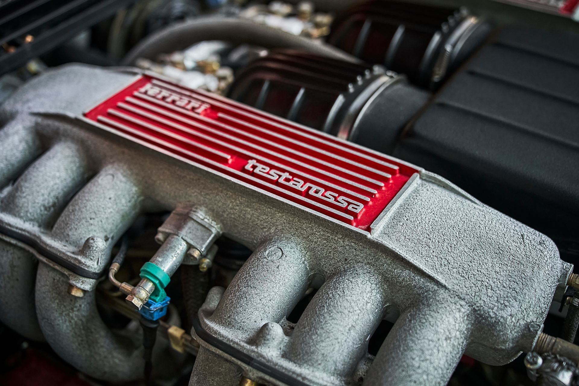 A close up of a ferrari engine with a red cover
