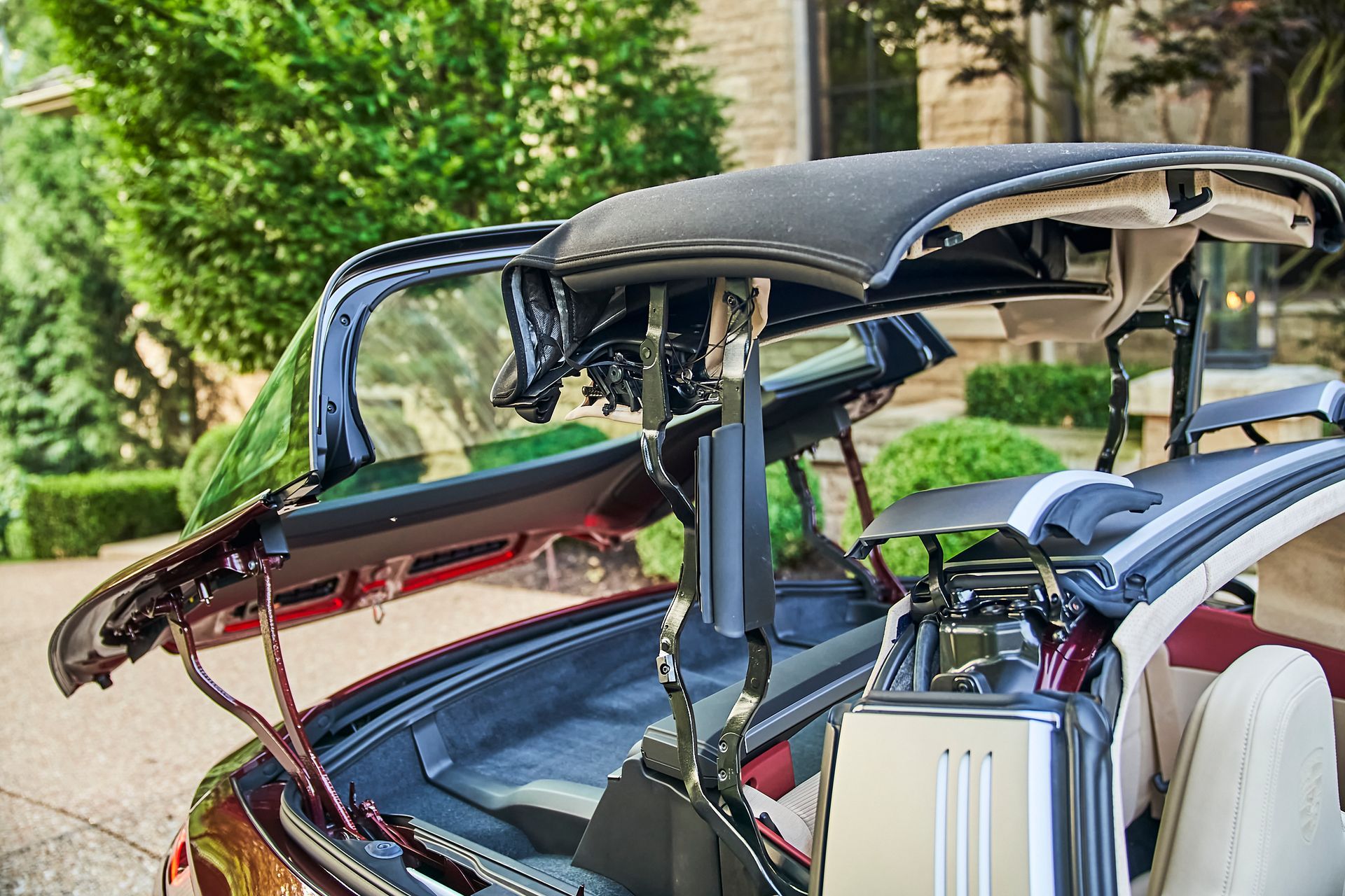 The trunk of a car is open and the roof is up.