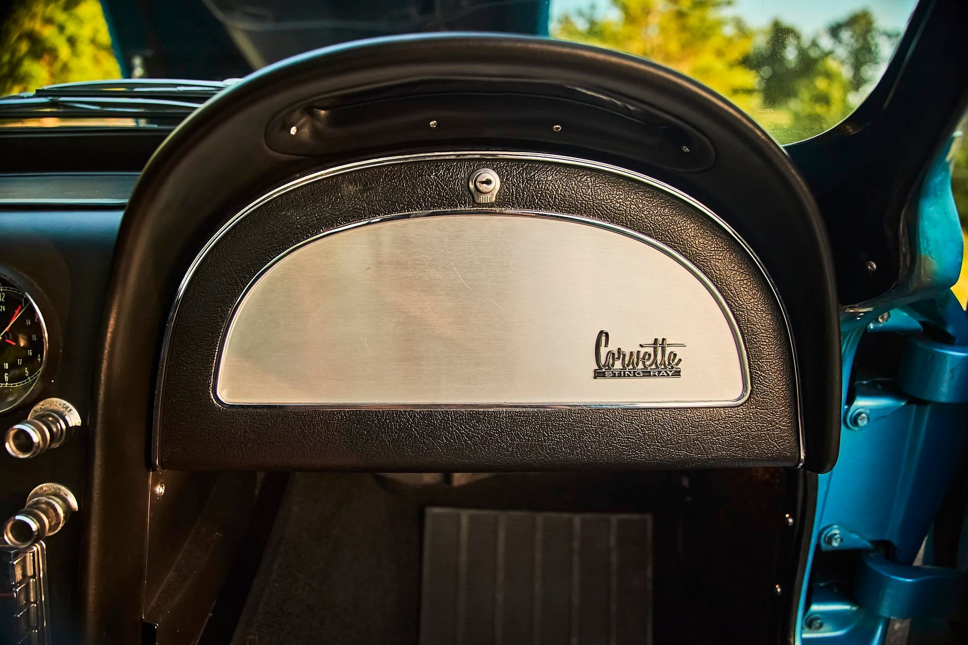 Dashboard of a classic Corvette with a silver panel and black trim. 