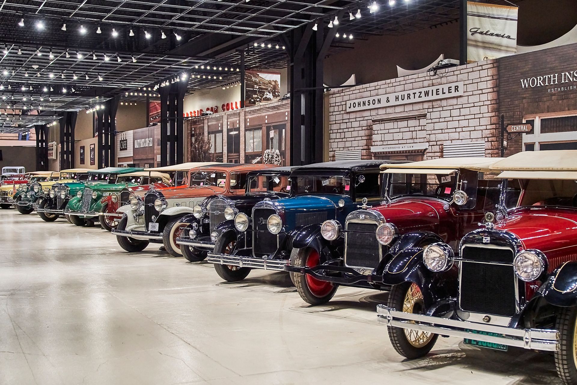 A row of old cars are parked in a garage.