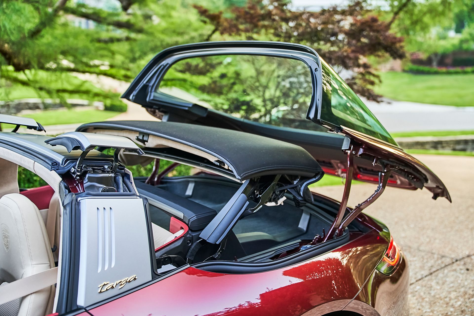 A red porsche targa with the roof up and the trunk open.
