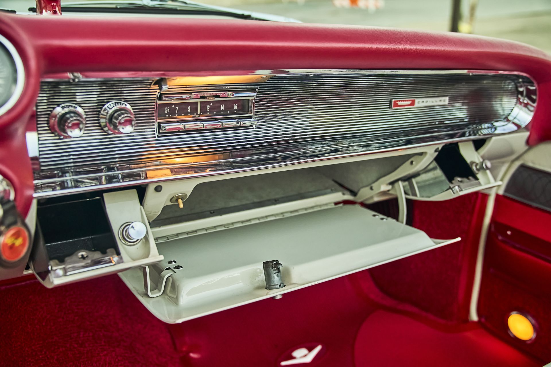 The glove box of a red car is open and empty.