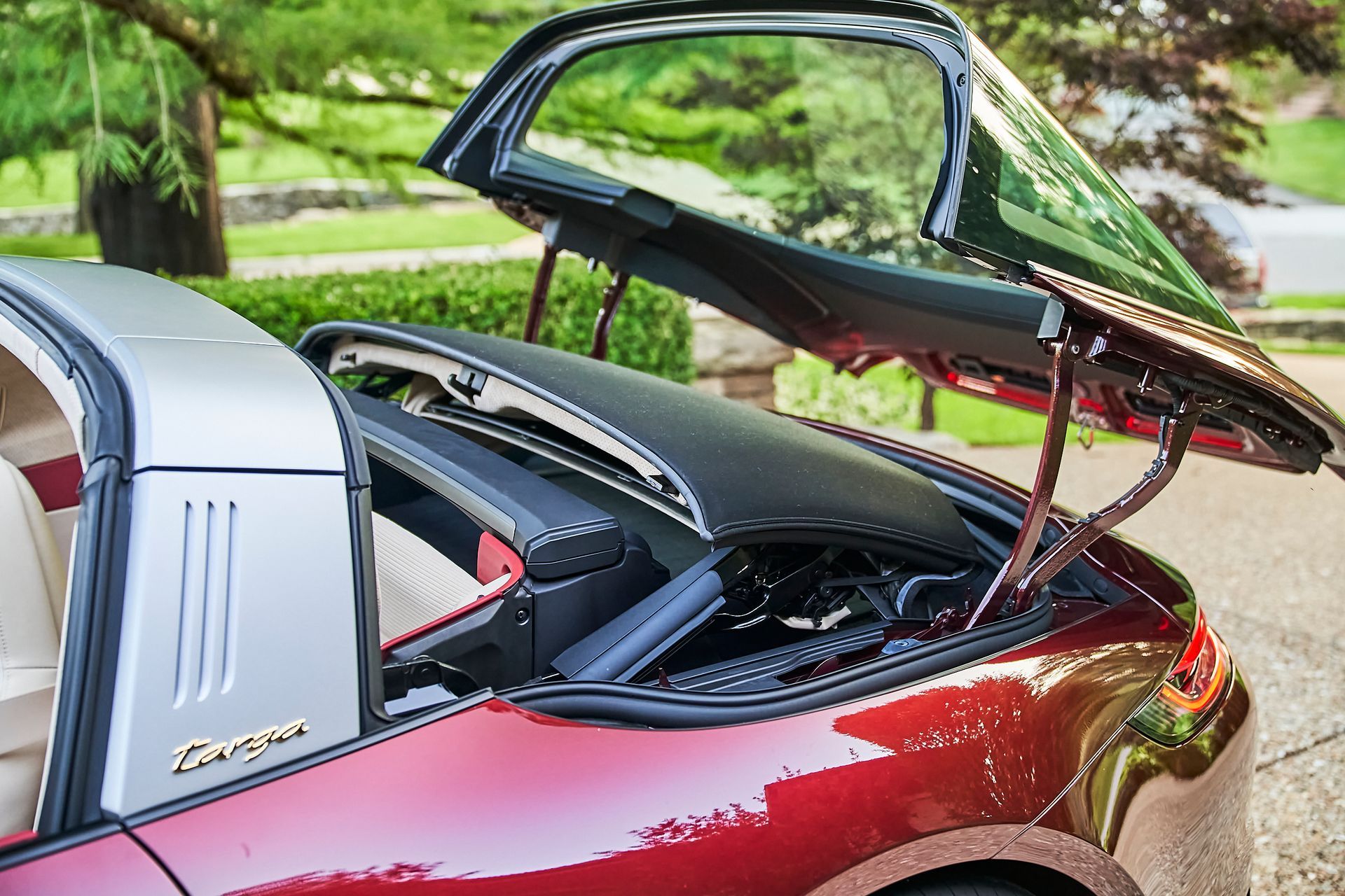 The trunk of a red porsche targa is open.