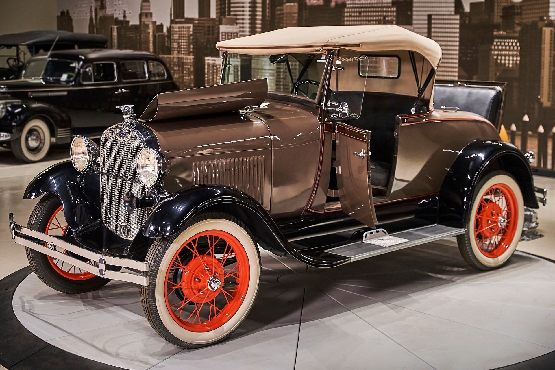 An old car with a convertible top is parked in a showroom.