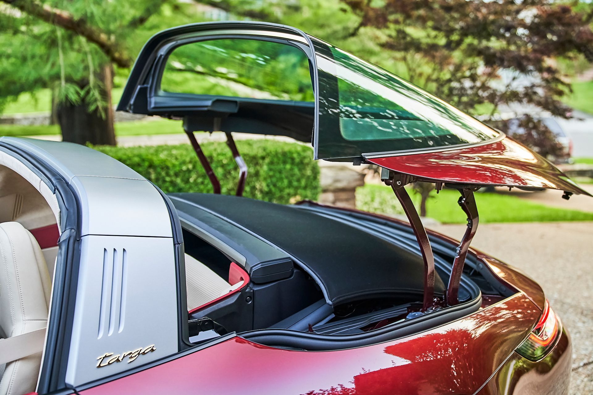 The trunk of a red porsche targa is open.