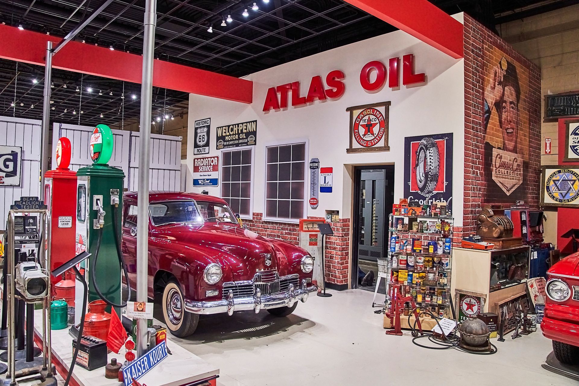 A red car is parked in a garage under a sign that says atlas oil