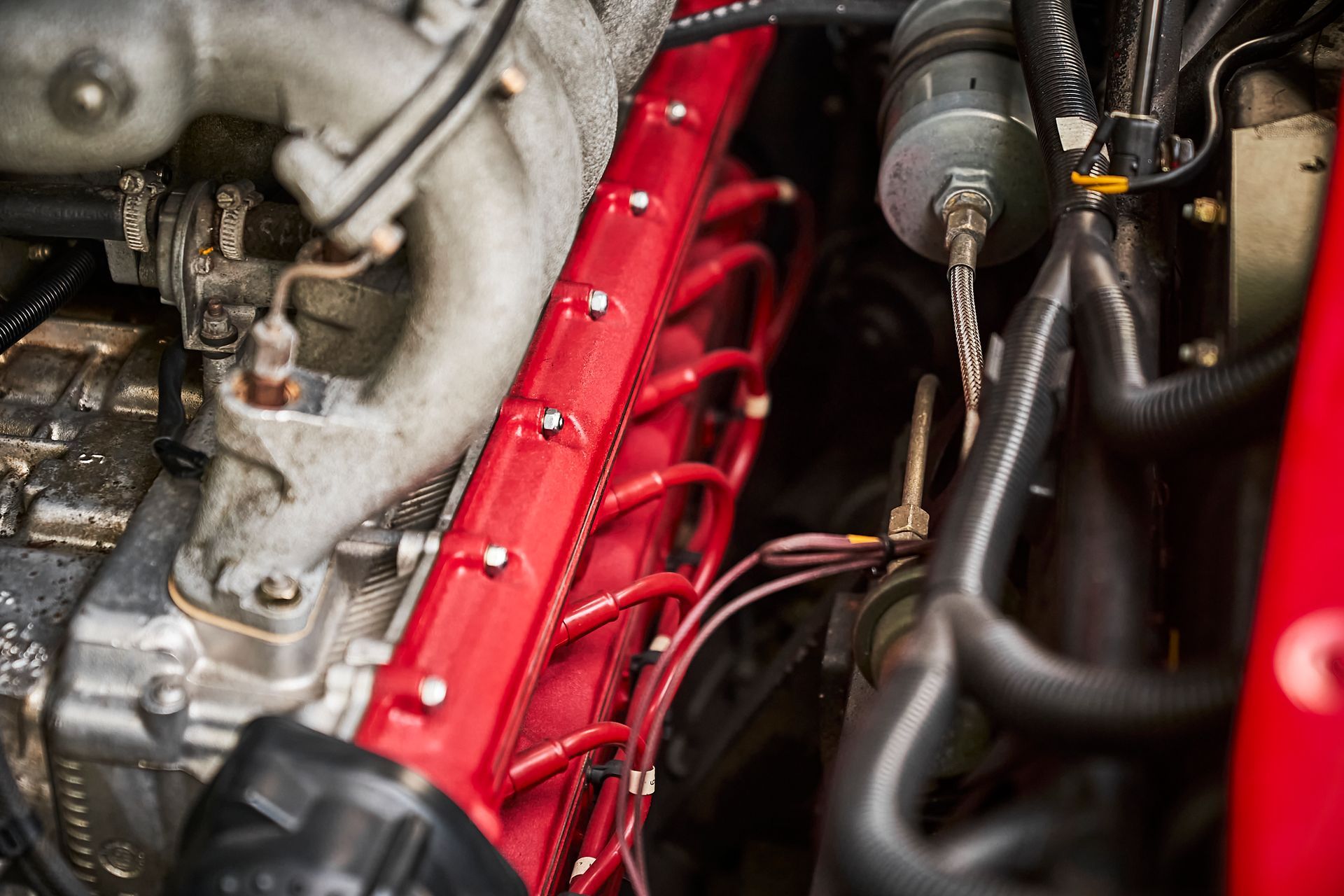 A close up of a red engine with a lot of wires coming out of it.