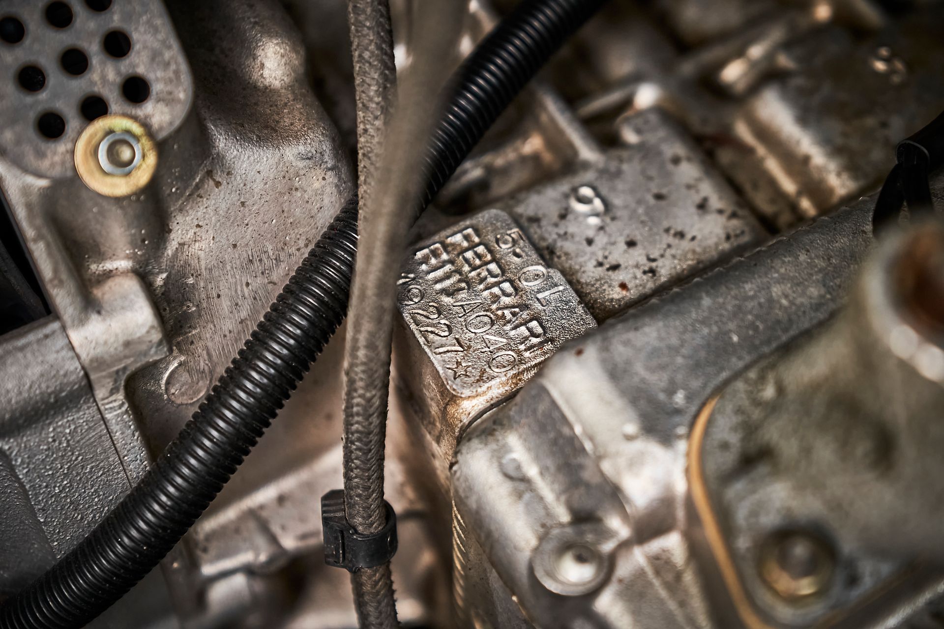 A close up of a car engine with a hose attached to it.