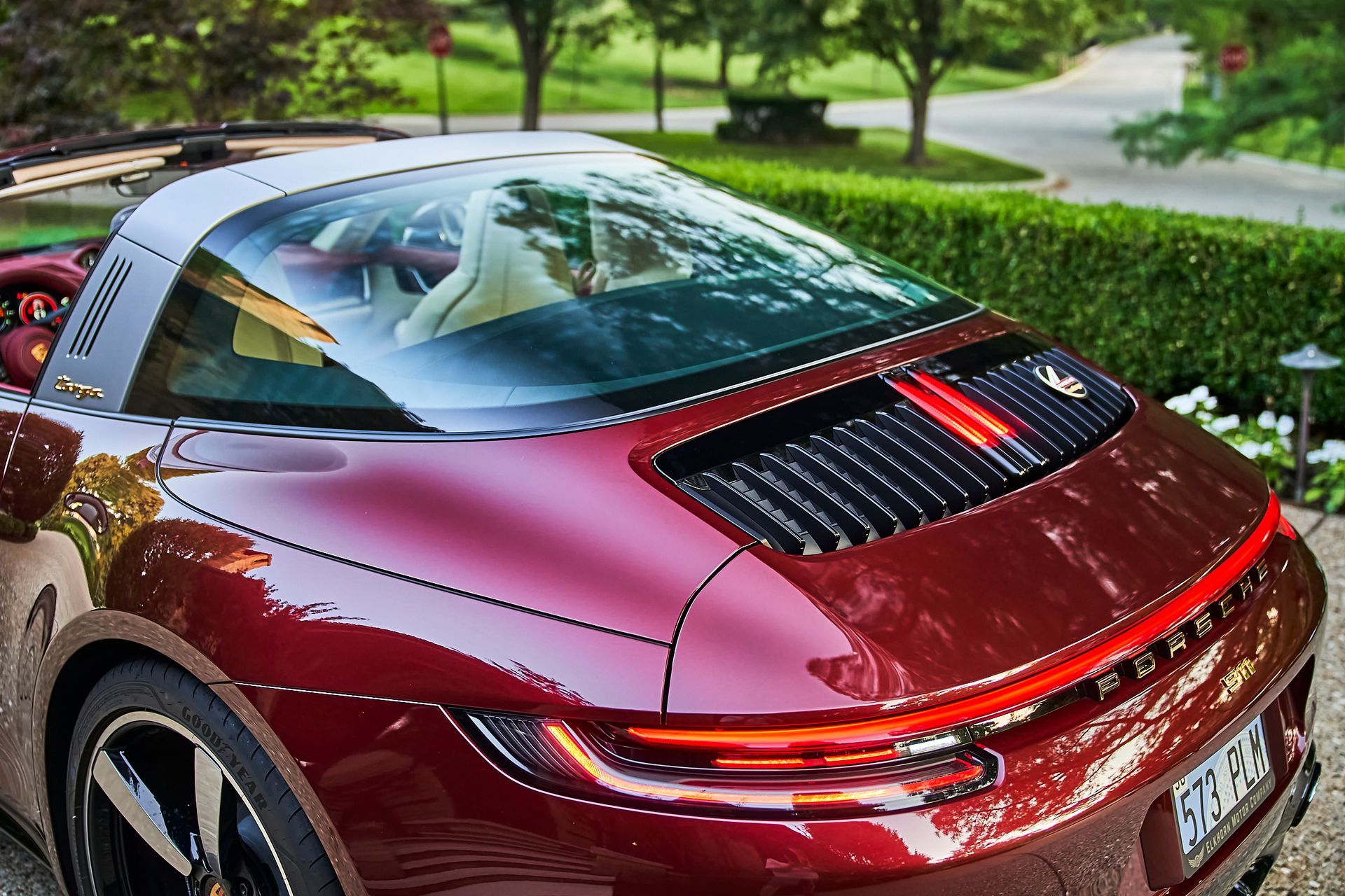 A red porsche targa is parked in a driveway.