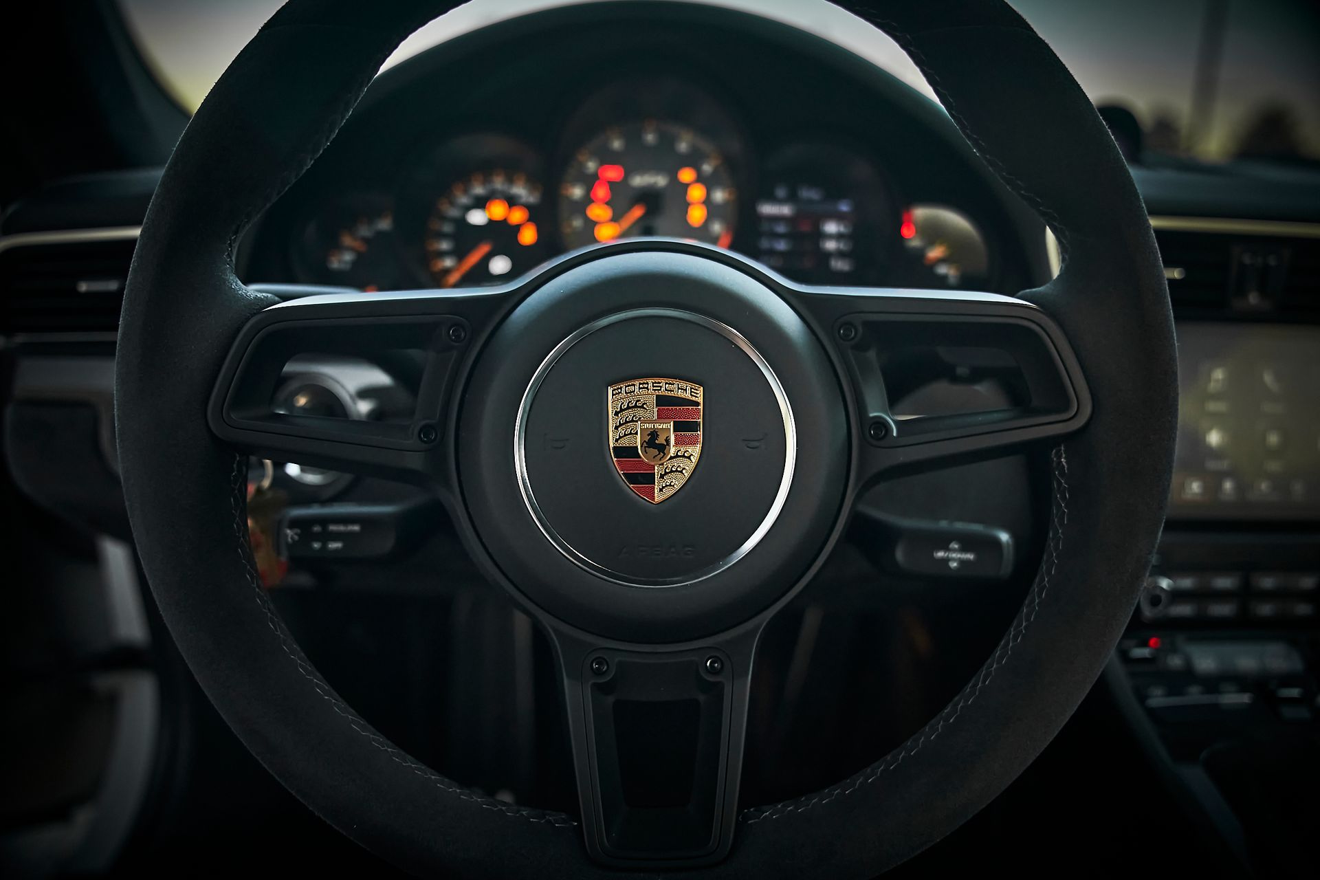 A close up of a porsche steering wheel in a car