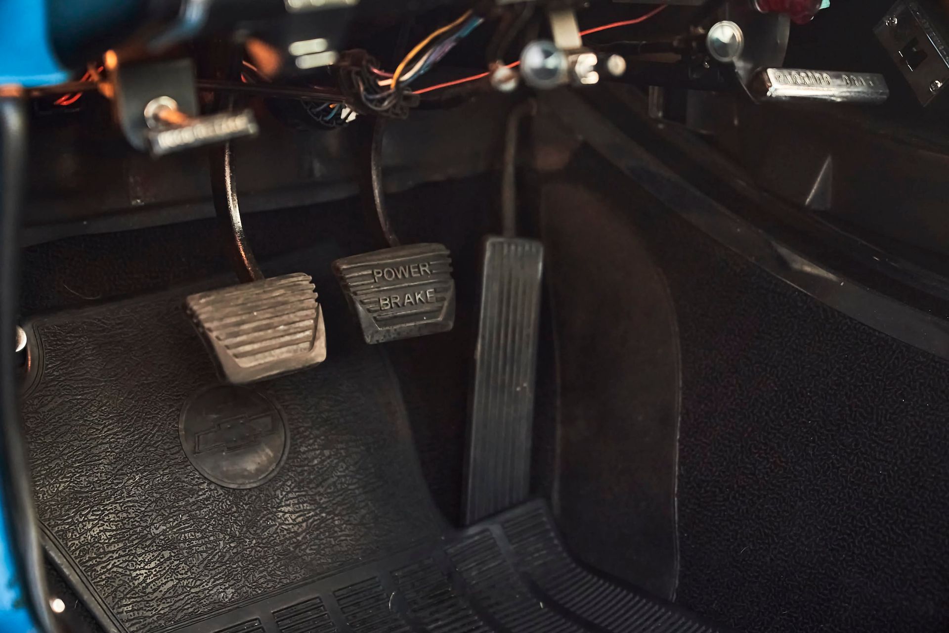Foot pedals of a vehicle; clutch, brake, and accelerator are visible. Interior shot with black and gray details.