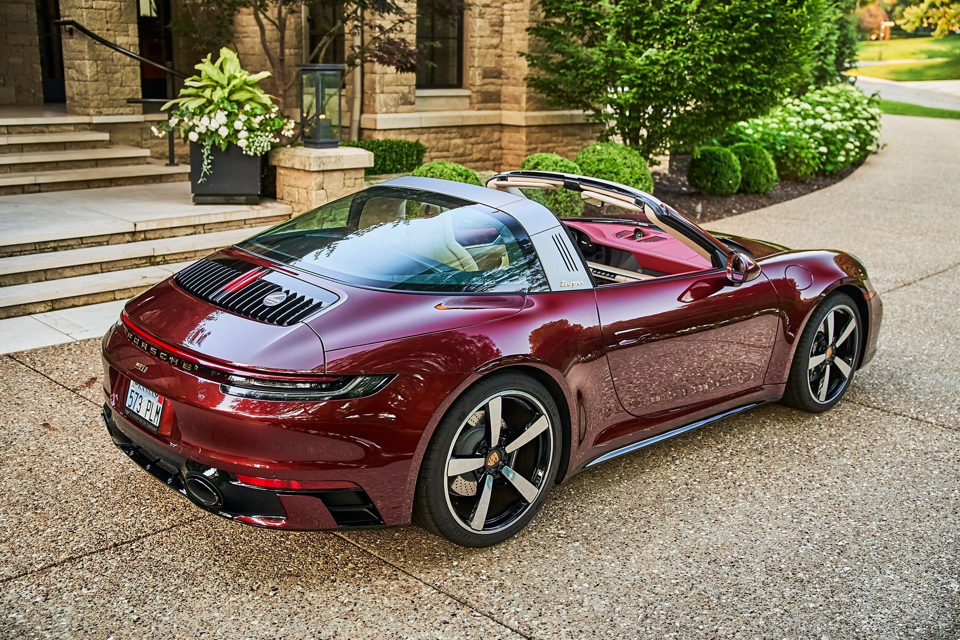 A red porsche targa is parked in front of a house.