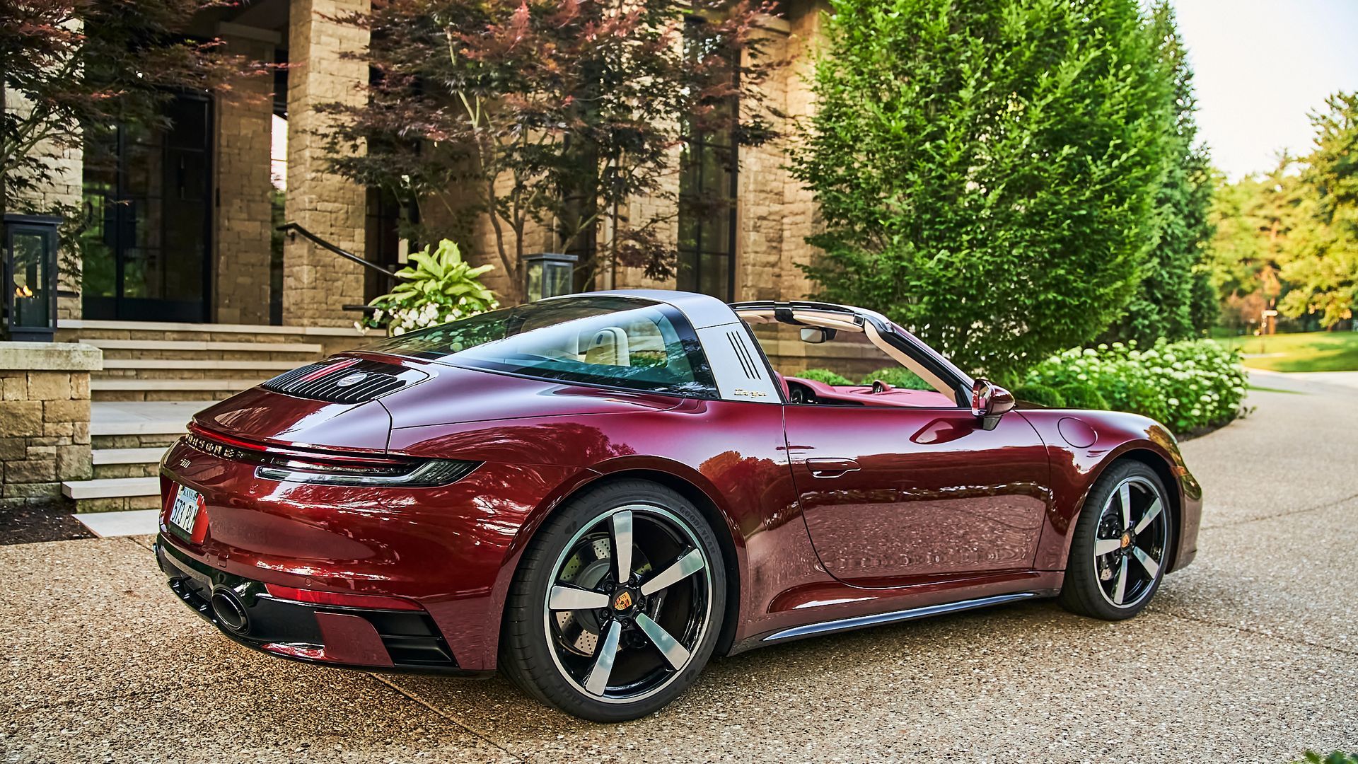A red porsche targa is parked in front of a building.