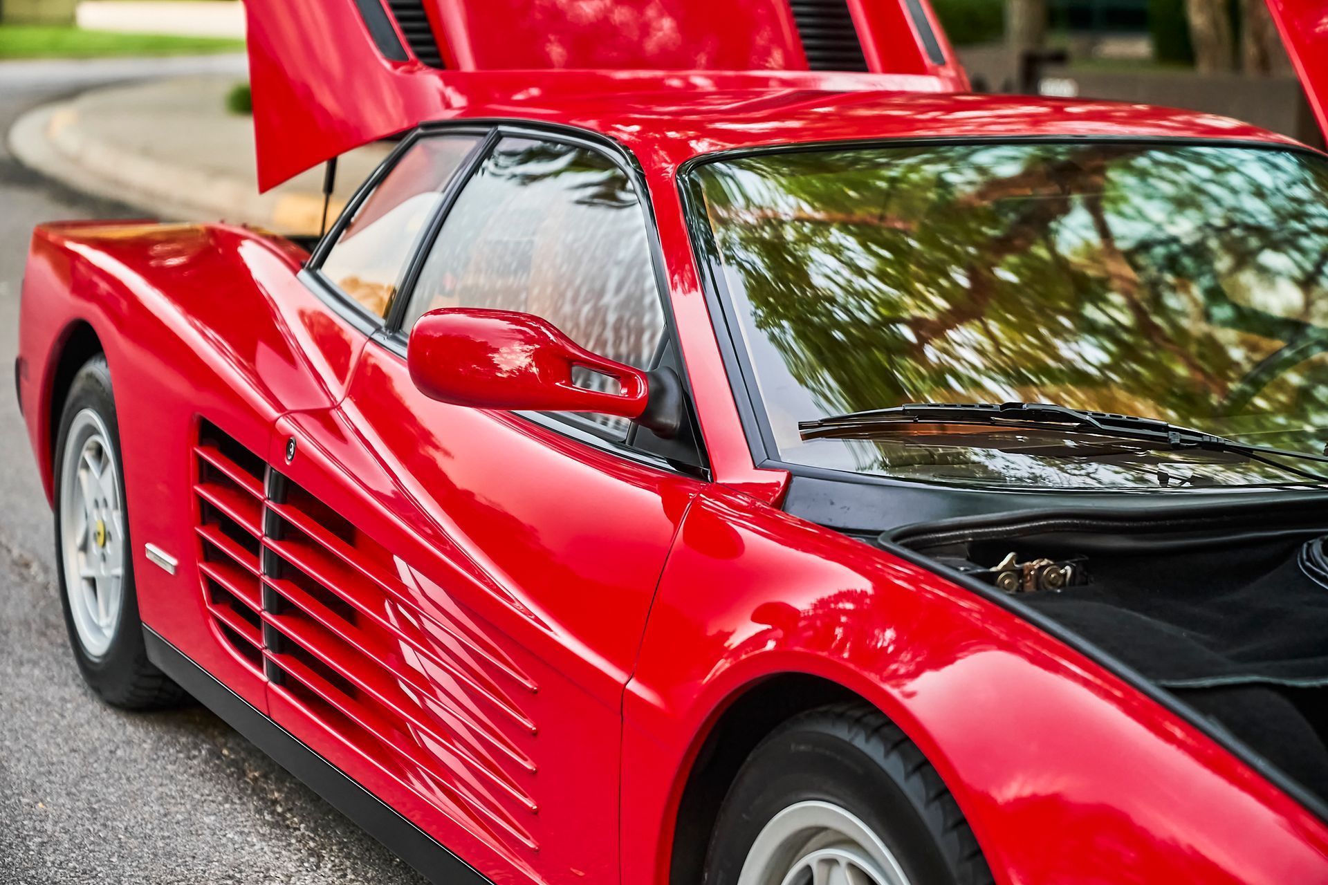 A red sports car with the hood up is parked on the street.