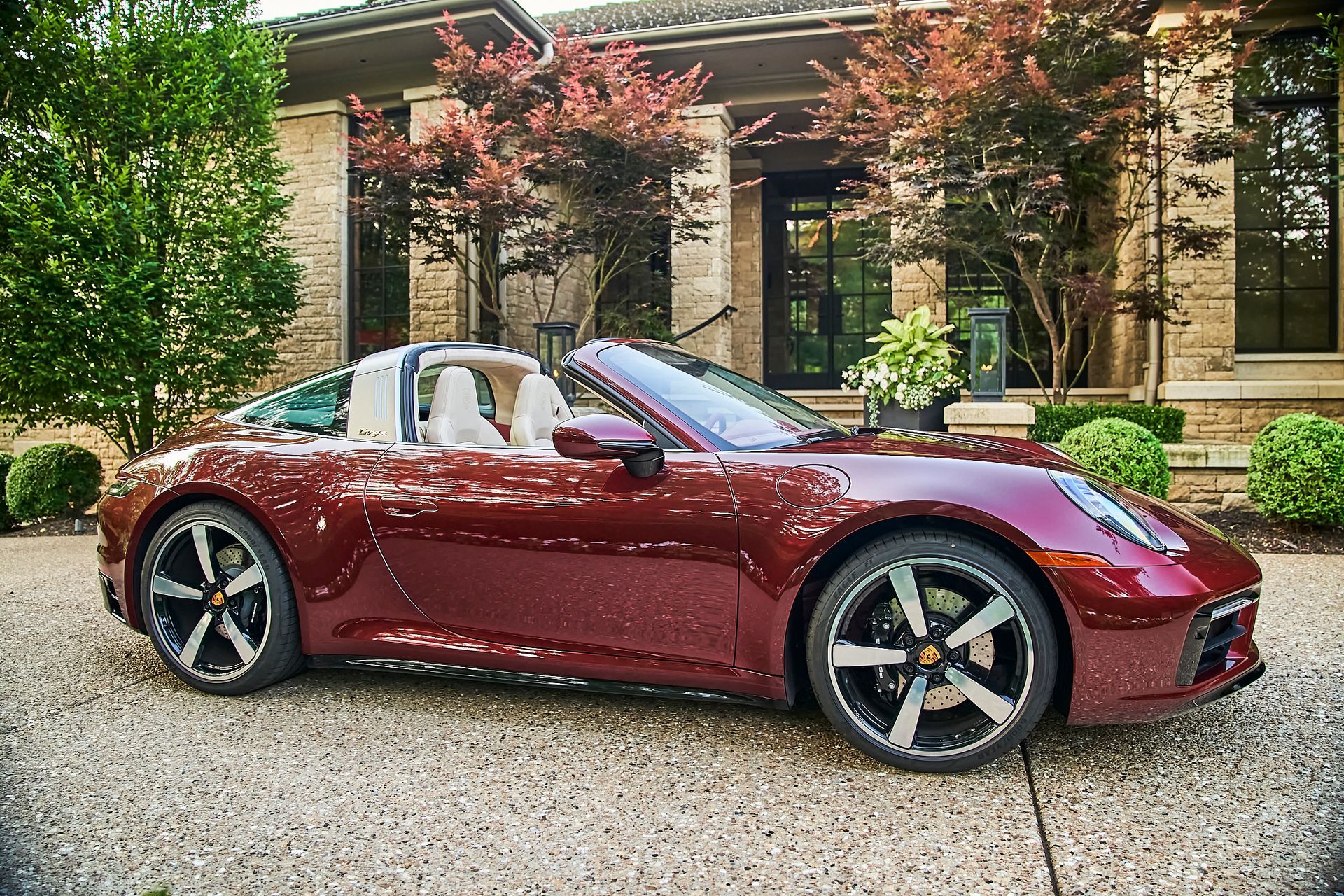 A red porsche targa is parked in front of a house.