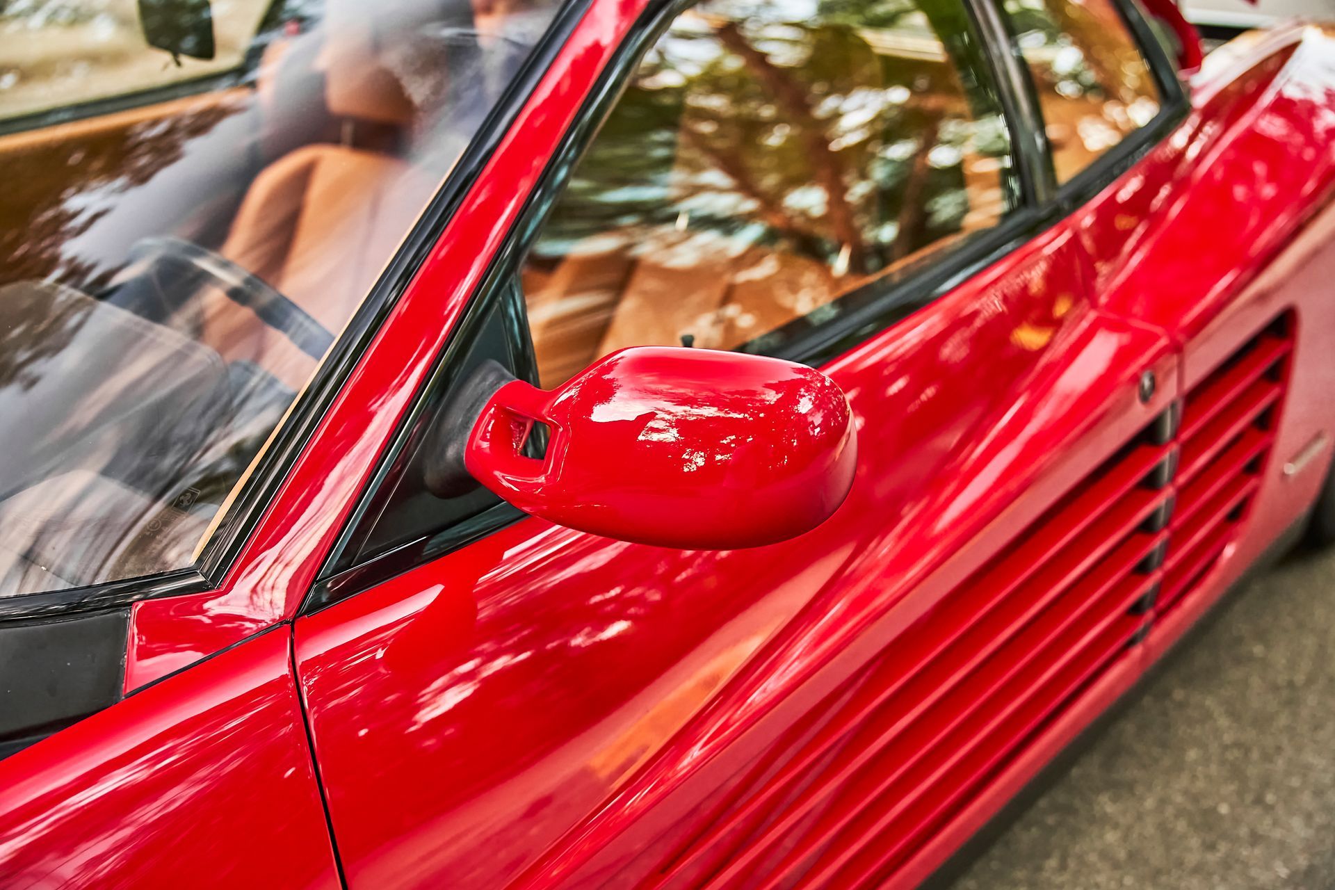 A close up of a red sports car parked on the side of the road.