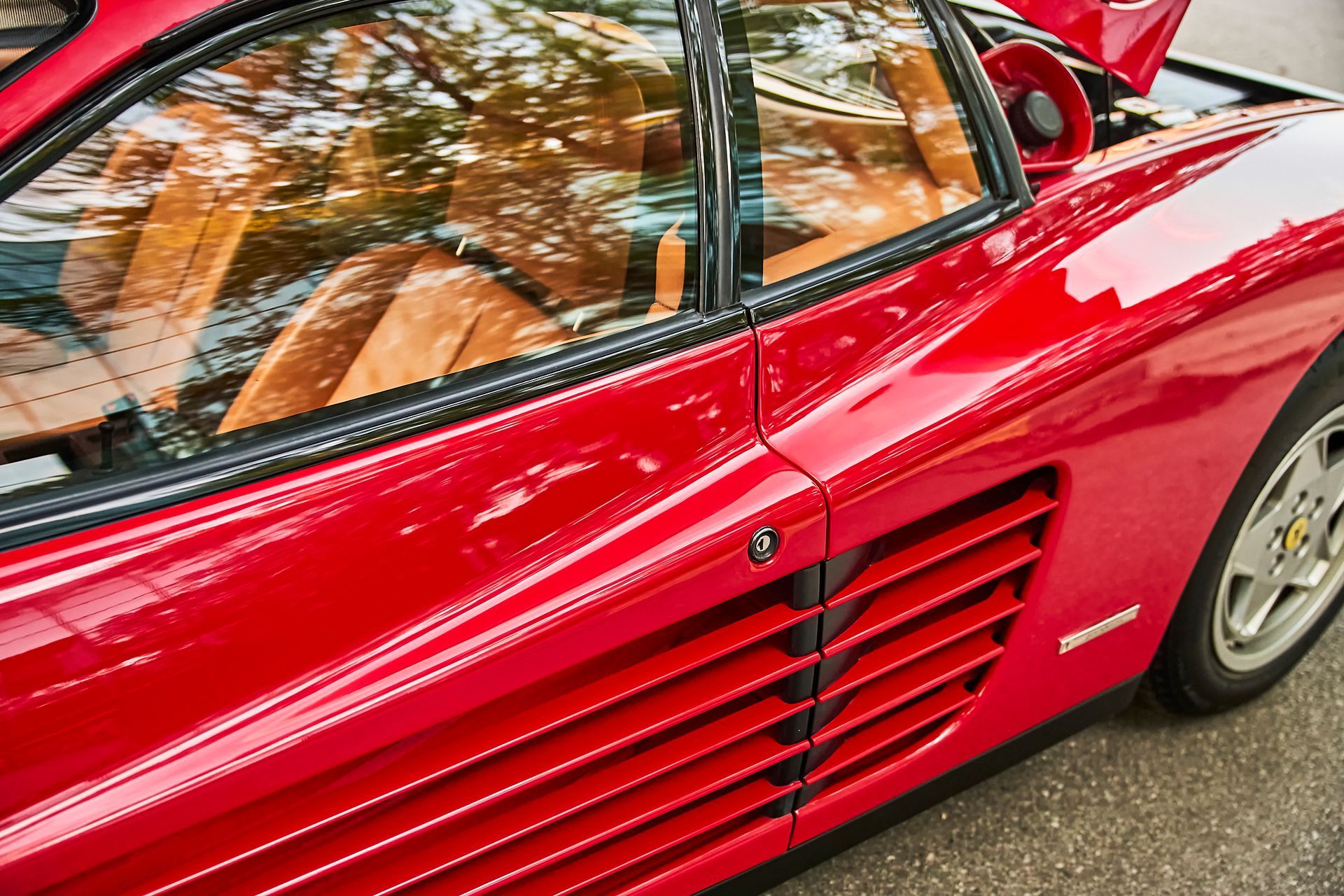 A red sports car with the hood up is parked on the side of the road.