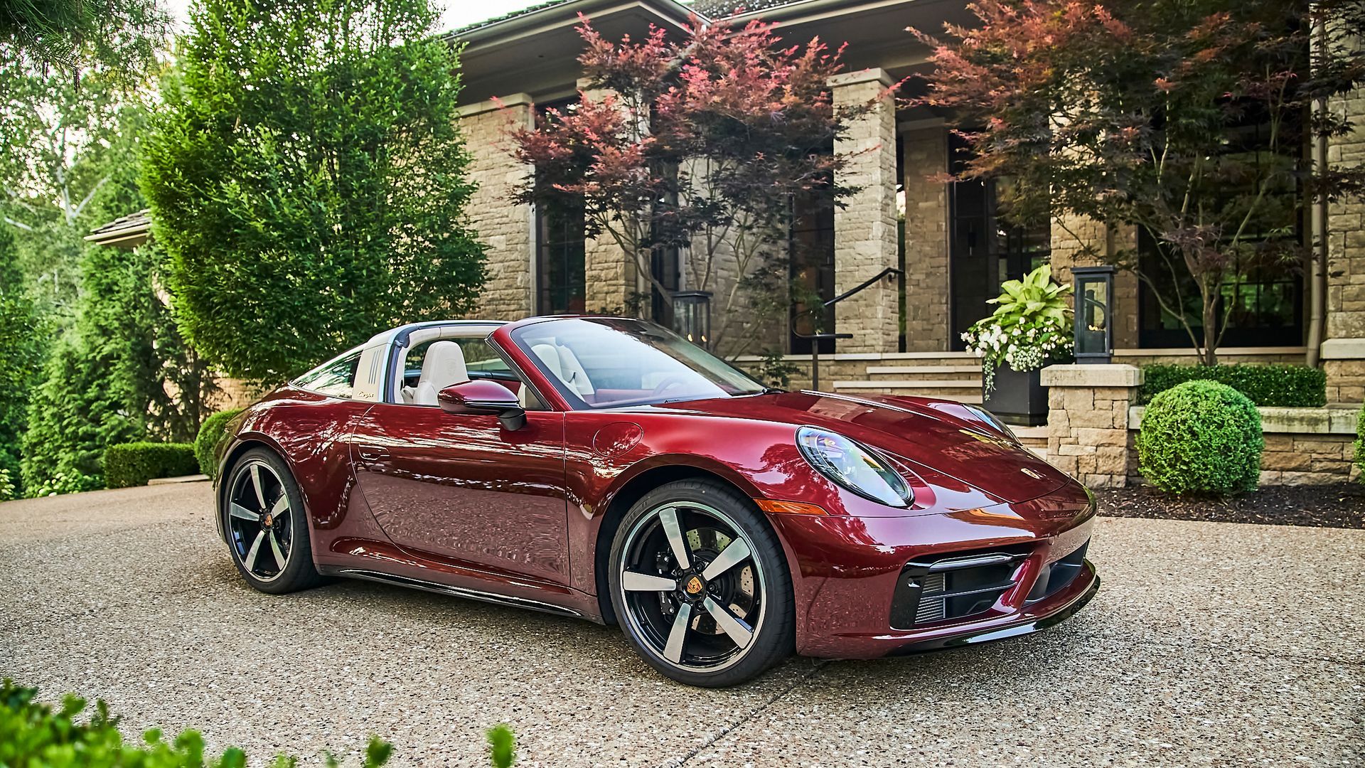 A red porsche targa is parked in front of a house.