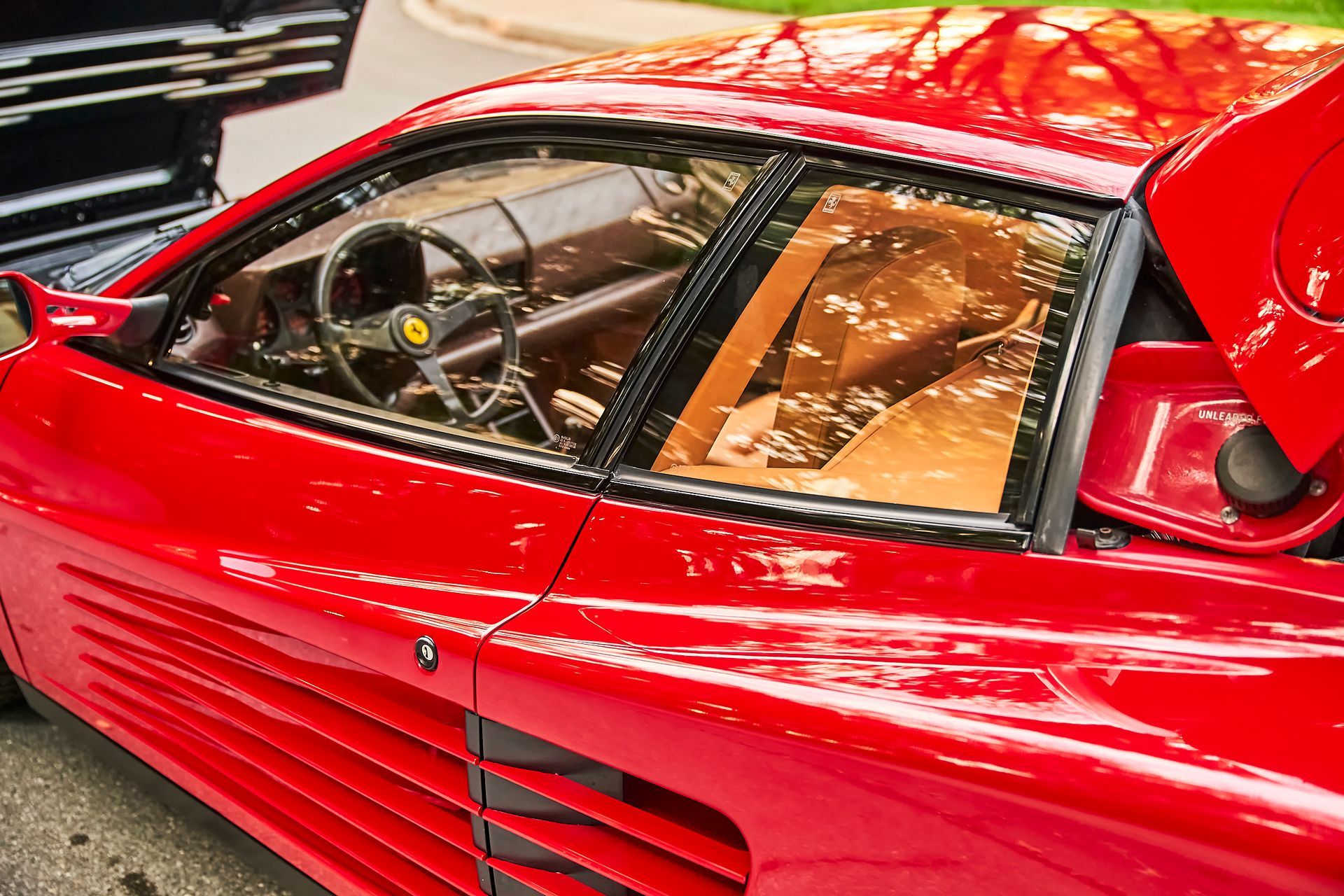 A red sports car with the hood up is parked on the side of the road.