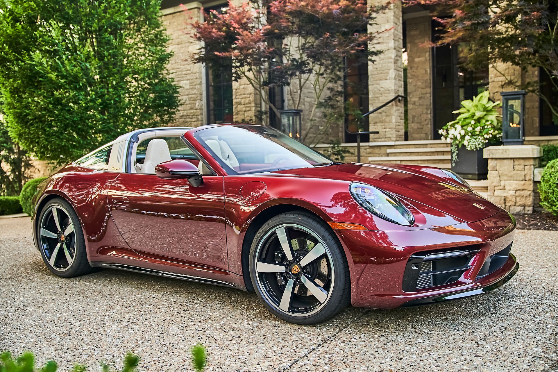 A red porsche targa is parked in front of a house.